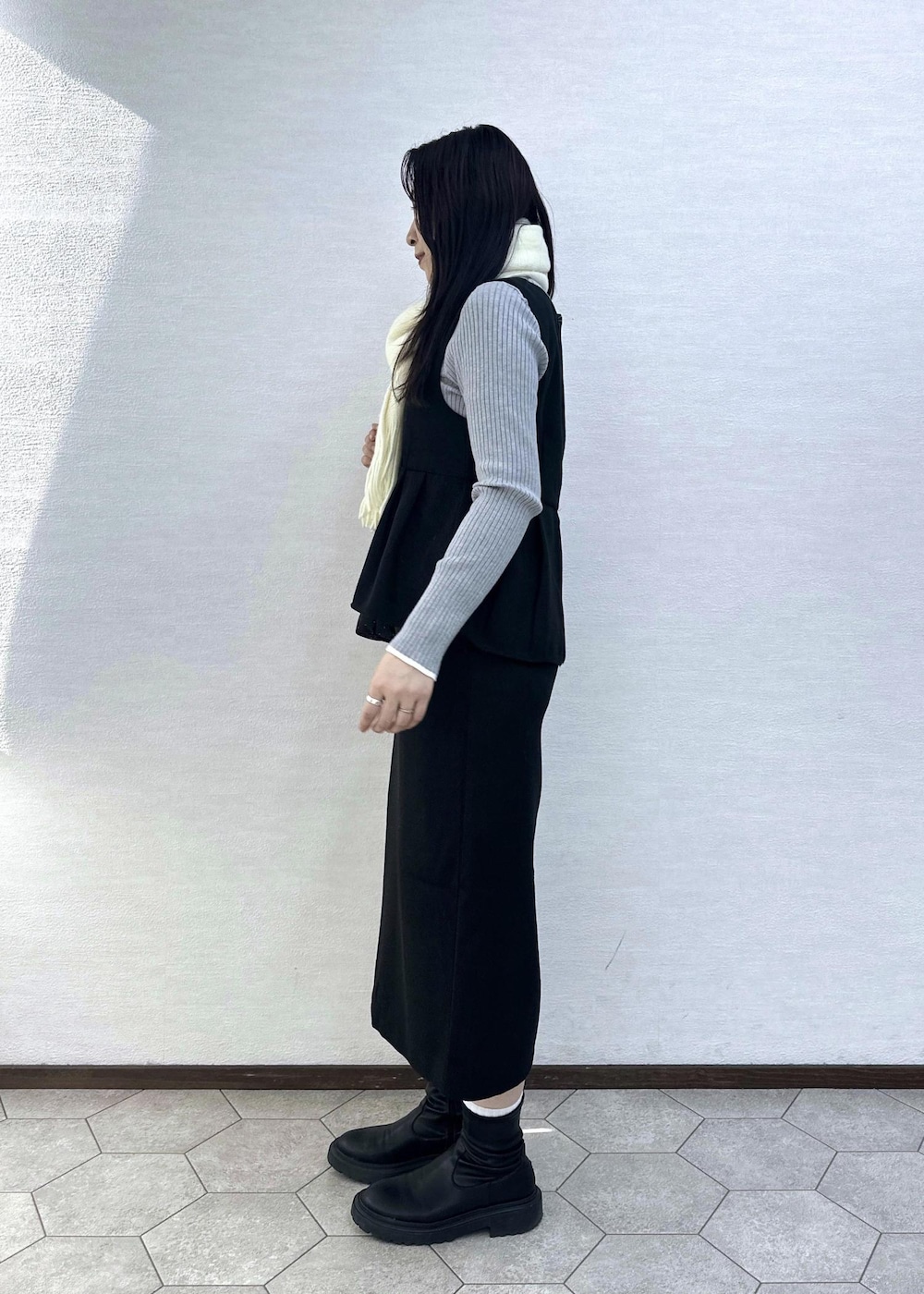 グレー系のニット/セーター、ブラック系のハンドバッグ、ブラック系のジャンパースカートを着用したレディースの冬コーディネートの5枚目の写真