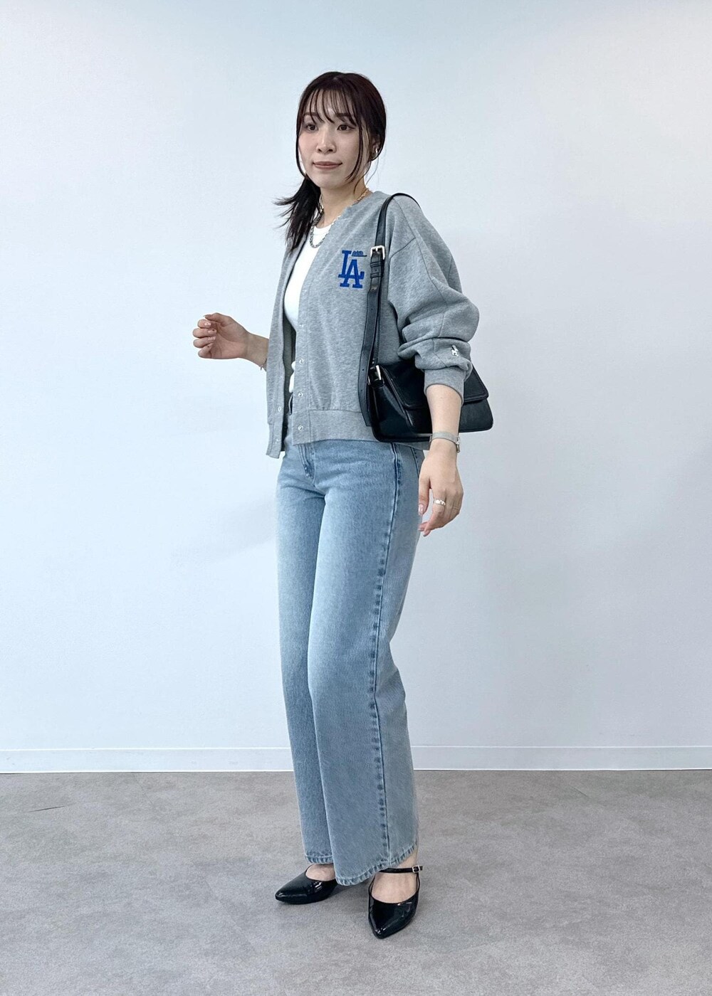 グレー系のデニムパンツ、ホワイト系のタンクトップ、ブラック系のショルダーバッグを着用したレディースの夏コーディネートの3枚目の写真