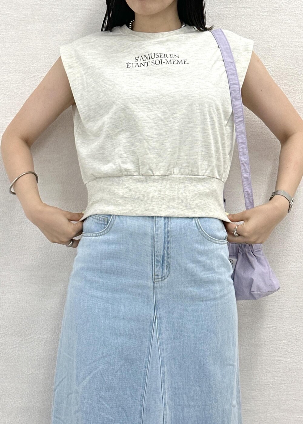 パープル系のショルダーバッグ、ホワイト系のスウェット、ブルー系のデニムスカートを着用したレディースの夏コーディネートの5枚目の写真