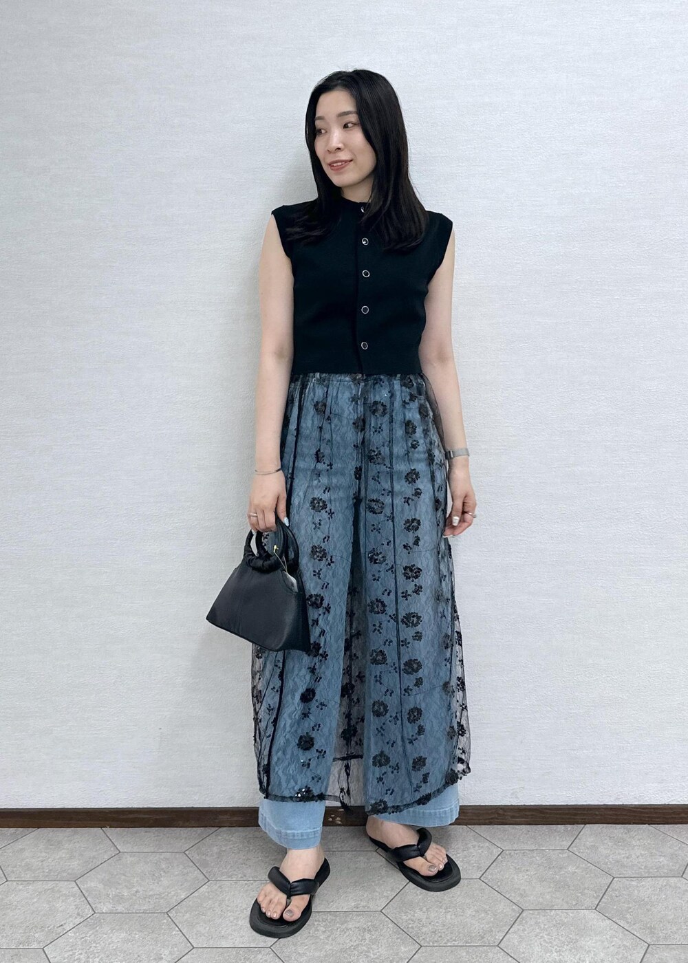 ブルー系のデニムパンツ、ブラック系のベスト、ブラック系のショルダーバッグを着用したレディースの夏コーディネートの3枚目の写真