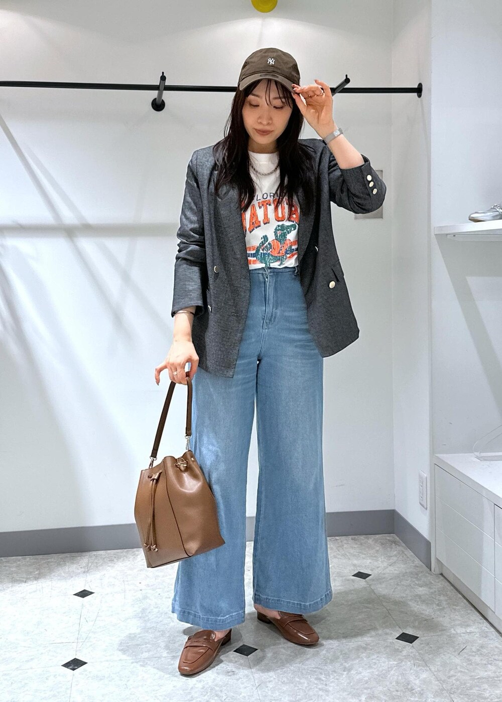 ブルー系のデニムパンツ、イエロー系のローファー、ブラウン系のショルダーバッグを着用したレディースの夏コーディネートの2枚目の写真