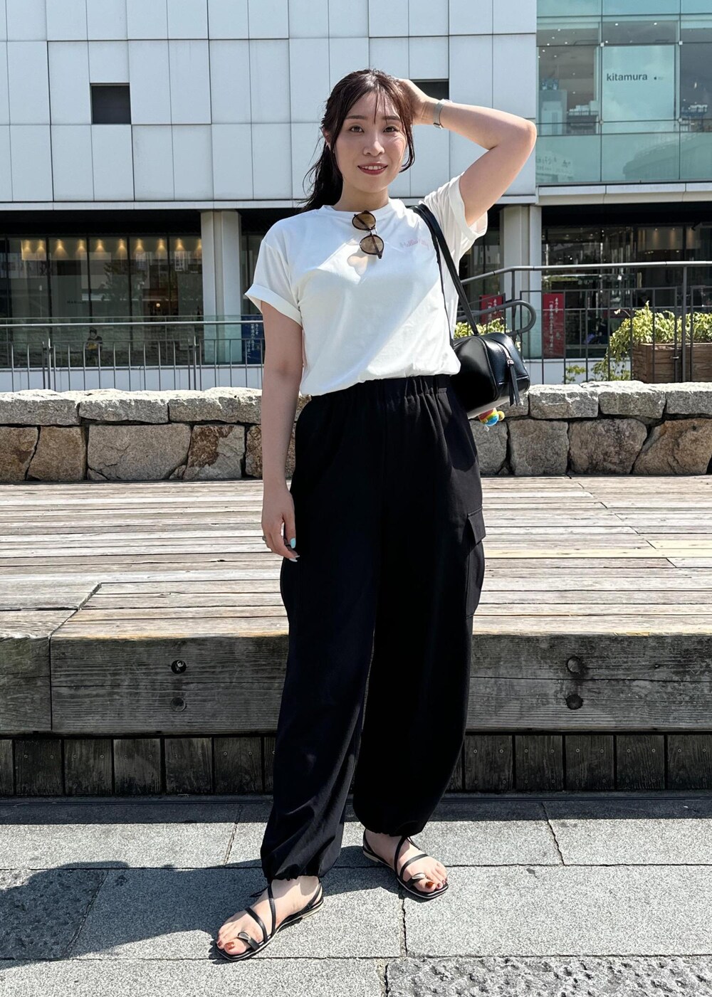 ブラック系のカーゴパンツ、ブラック系のサンダル、ホワイト系のTシャツ/カットソーを着用したレディースの夏コーディネートの3枚目の写真
