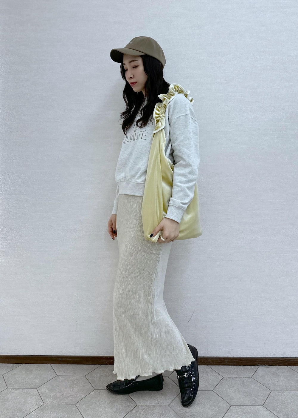 イエロー系のショルダーバッグ、グレー系のスウェット、ホワイト系のスカートを着用したレディースの冬コーディネートの4枚目の写真