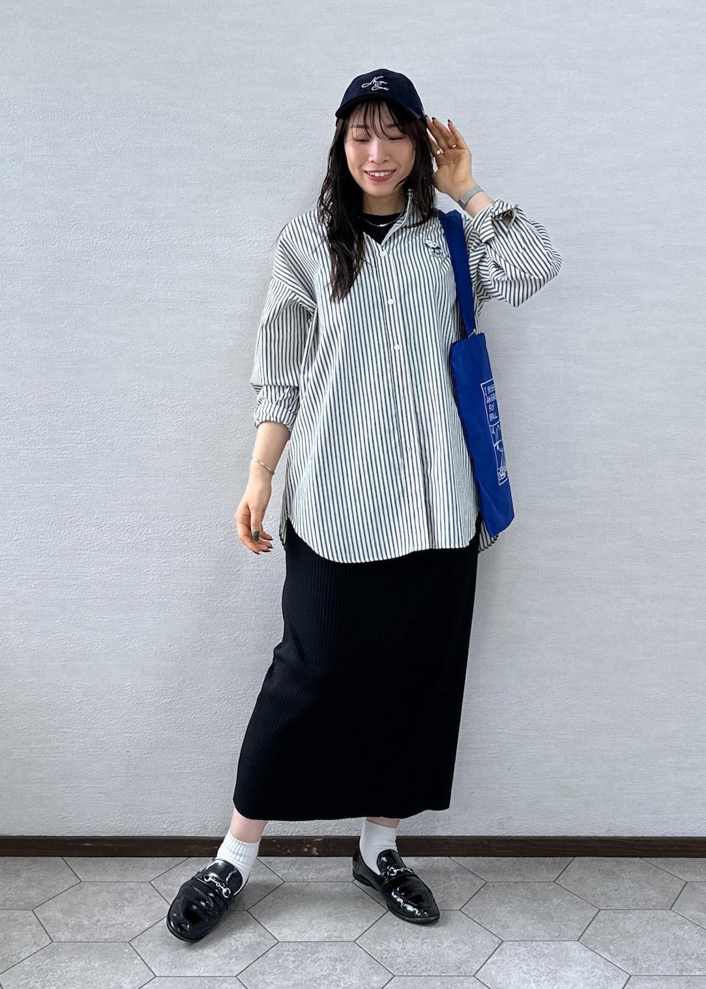 ブラック系のスカート、ホワイト系のシャツ/ブラウス、ブルー系のトートバッグを着用したレディースの秋コーディネートの2枚目の写真
