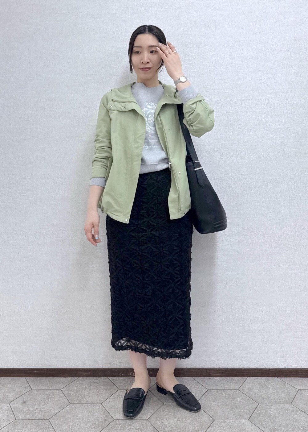 ブラック系のスカート、グレー系のニット/セーター、グリーン系のマウンテンパーカーを着用したレディースの春コーディネートの4枚目の写真