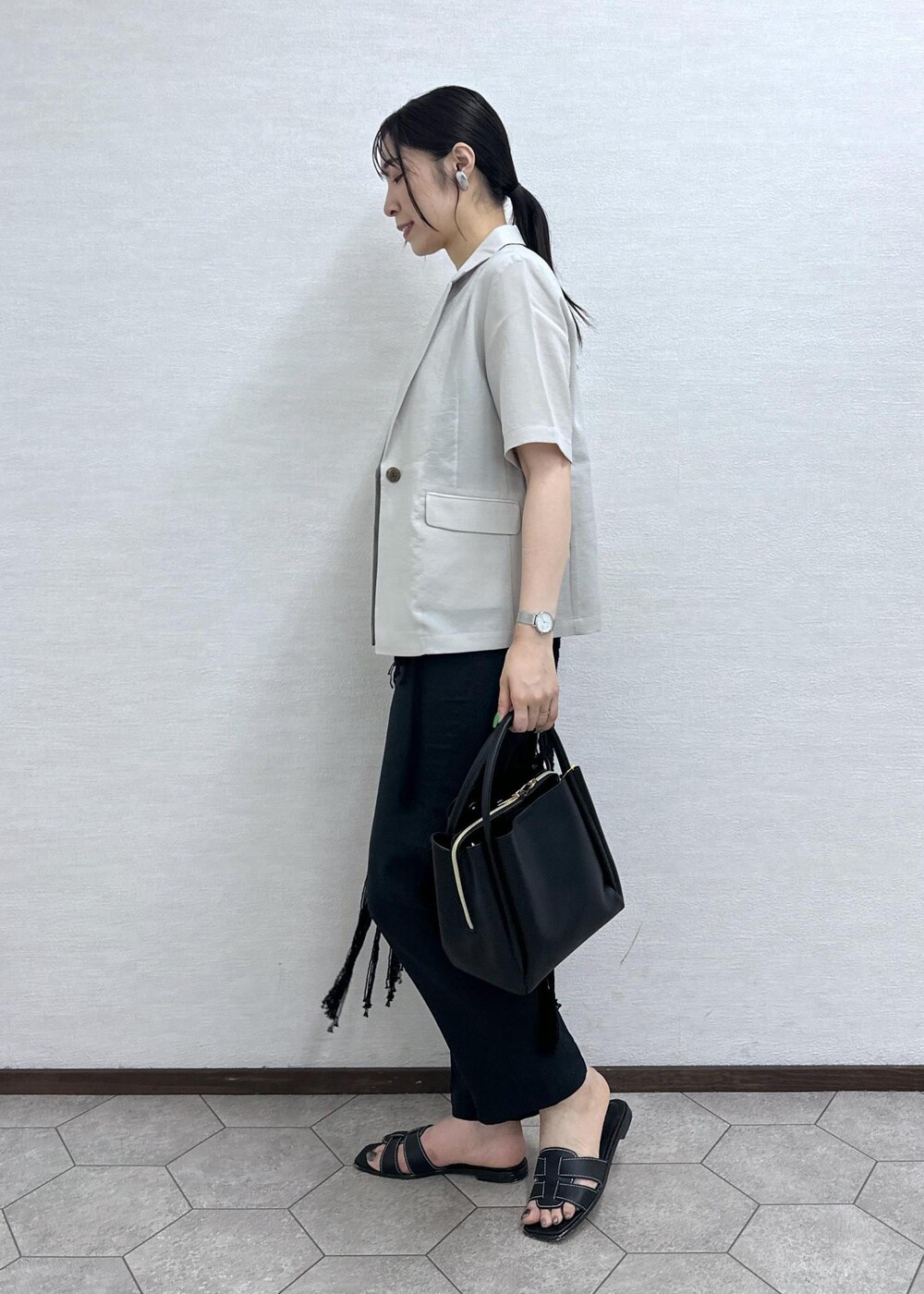 ブラック系のショルダーバッグ、ベージュ系のテーラードジャケット、グレー系のその他パンツを着用したレディースの夏コーディネートの6枚目の写真