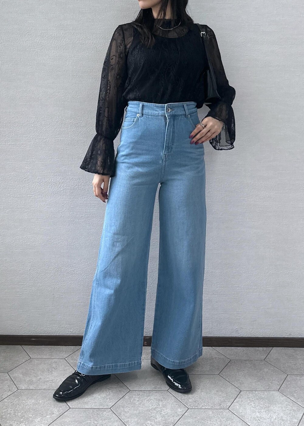 ブルー系のデニムパンツ、ブラック系のショルダーバッグ、ブラック系のシャツ/ブラウスを着用したレディースの秋コーディネートの5枚目の写真