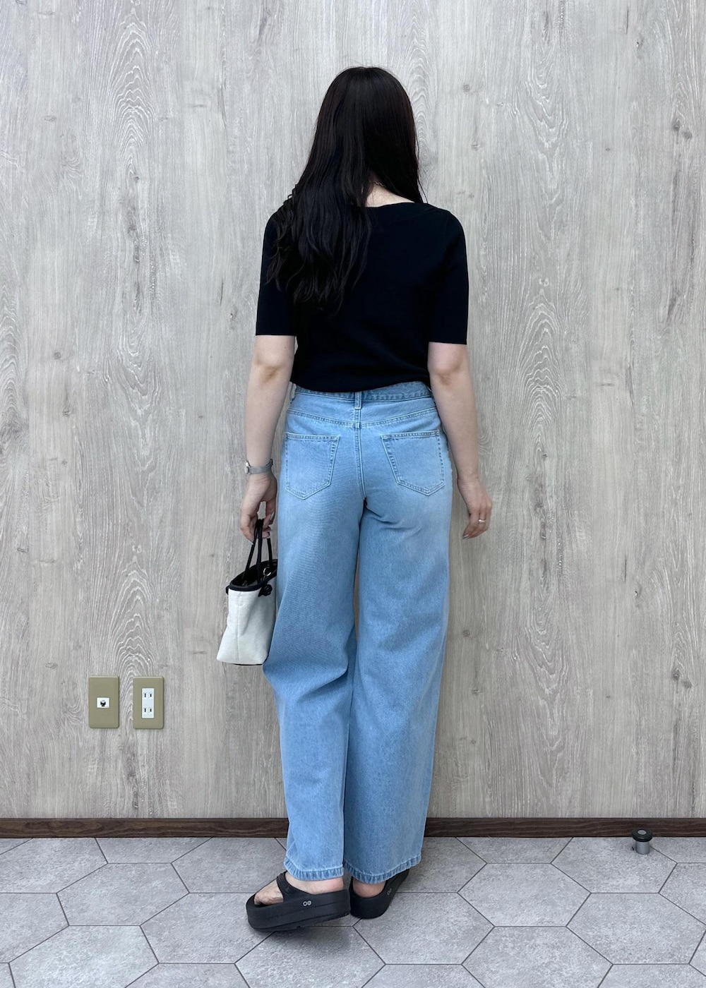 ブルー系のデニムパンツ、ブラック系のニット/セーター、ブラック系のトートバッグを着用したレディースの夏コーディネートの6枚目の写真