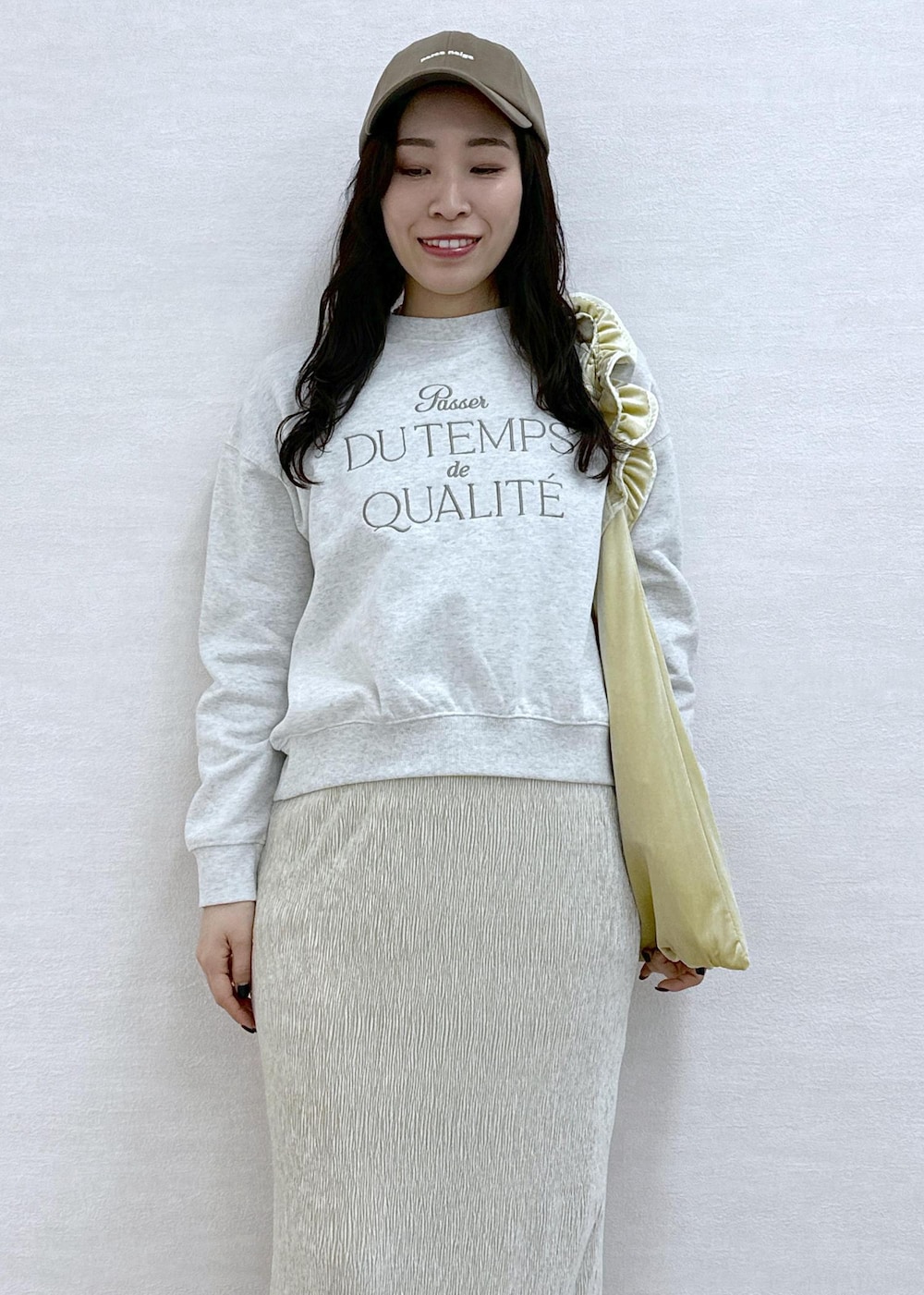 イエロー系のショルダーバッグ、グレー系のスウェット、ホワイト系のスカートを着用したレディースの冬コーディネートの5枚目の写真