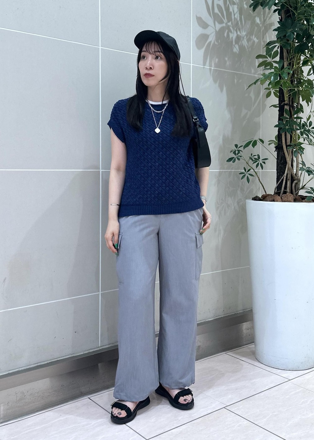 ブルー系のベスト、グレー系のカーゴパンツ、ブラック系のサンダルを着用したレディースの夏コーディネートの2枚目の写真