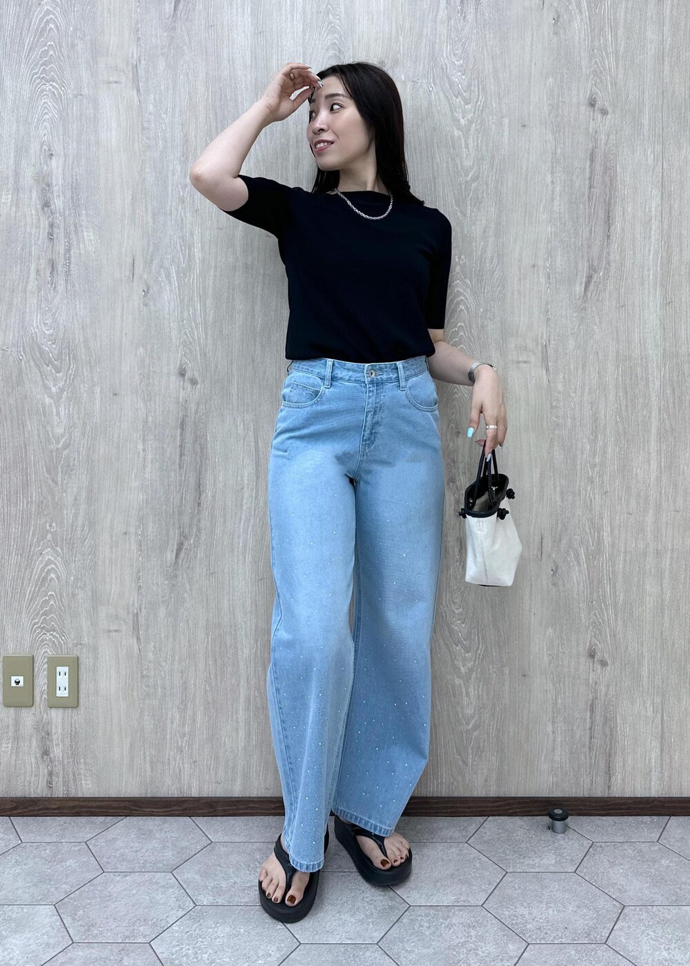 ブルー系のデニムパンツ、ブラック系のニット/セーター、ブラック系のトートバッグを着用したレディースの夏コーディネートの4枚目の写真