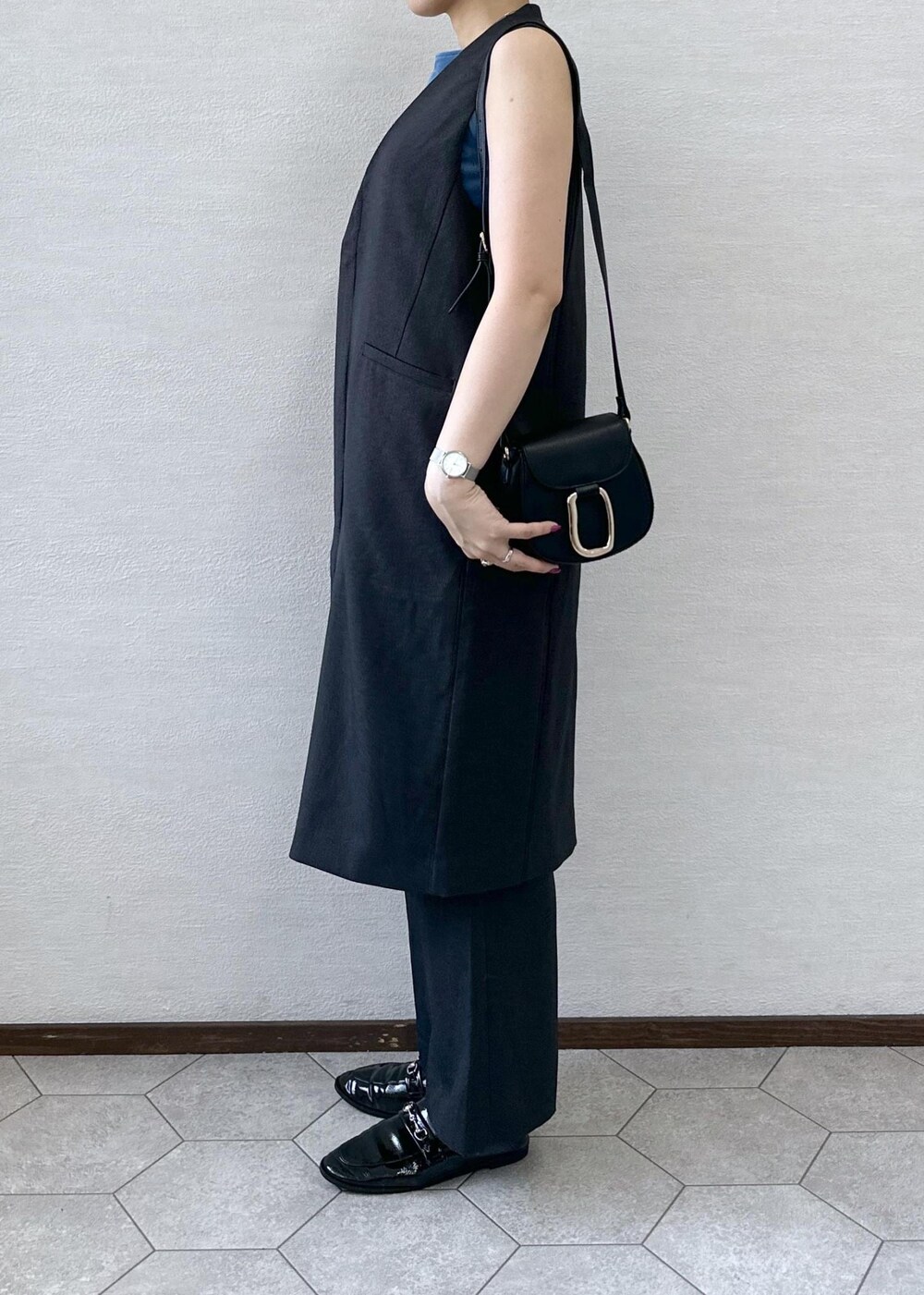 ブラック系のショルダーバッグ、ブルー系のTシャツ/カットソー、グレー系のベストを着用したレディースの秋コーディネートの6枚目の写真