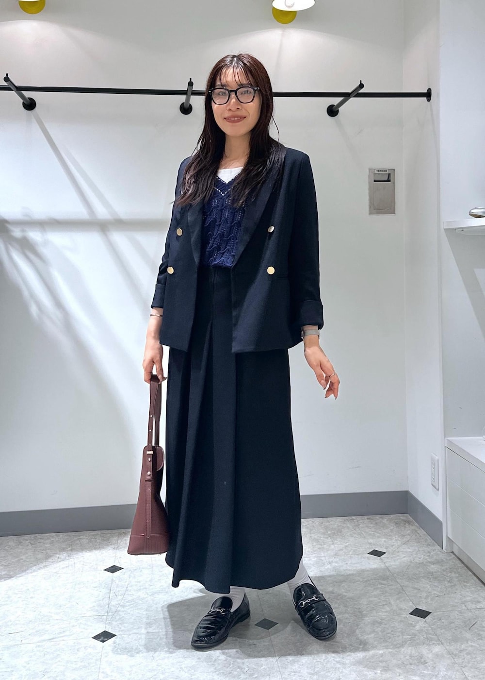 ブルー系のベスト、レッド系のショルダーバッグ、ホワイト系のタンクトップを着用したレディースの夏コーディネートの5枚目の写真