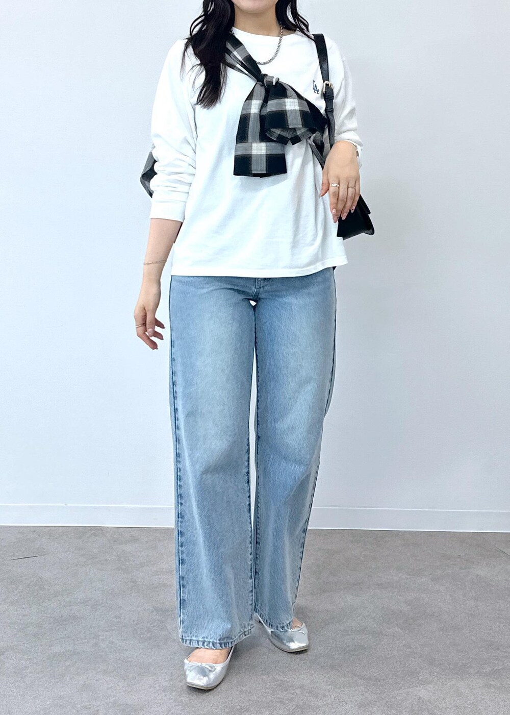 ブルー系のデニムパンツ、シルバー系のバレエシューズ、ブラック系のショルダーバッグを着用したレディースの夏コーディネートの6枚目の写真