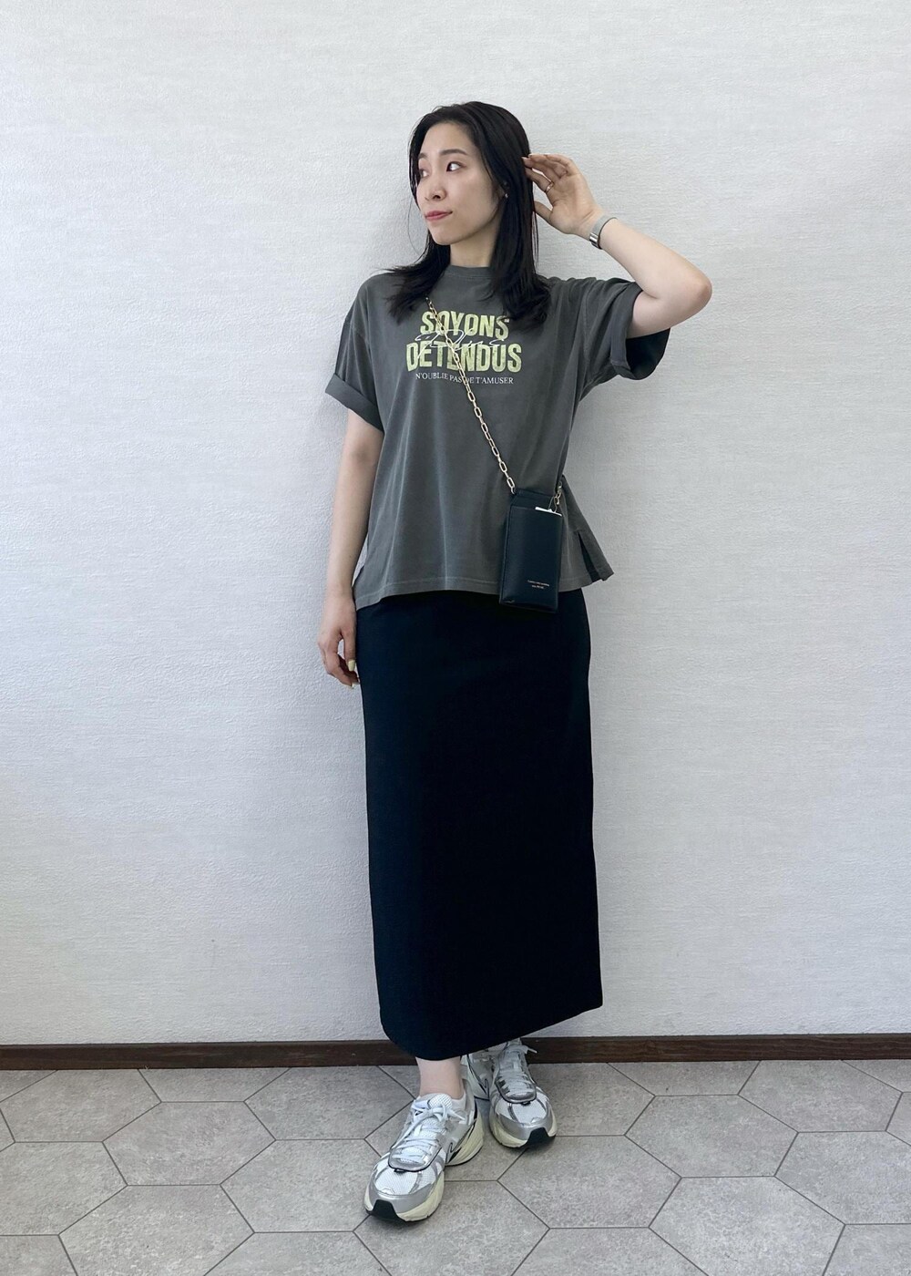 ブラック系のスカート、グレー系のTシャツ/カットソー、ブラック系のショルダーバッグを着用したレディースの夏コーディネートの2枚目の写真
