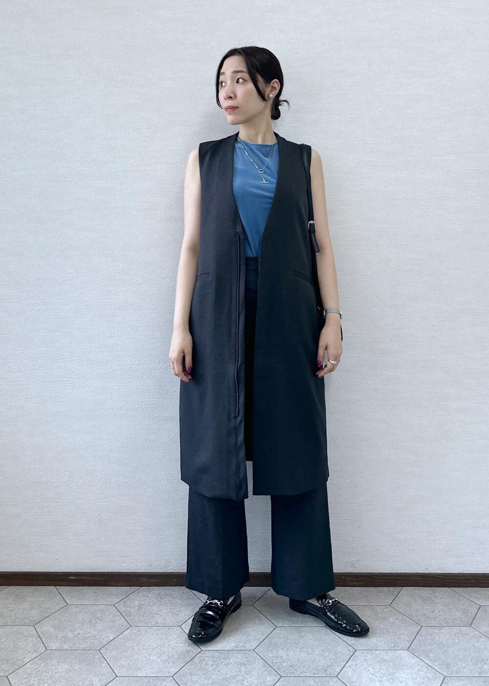 ブラック系のショルダーバッグ、ブルー系のTシャツ/カットソー、グレー系のベストを着用したレディースの秋コーディネートの3枚目の写真