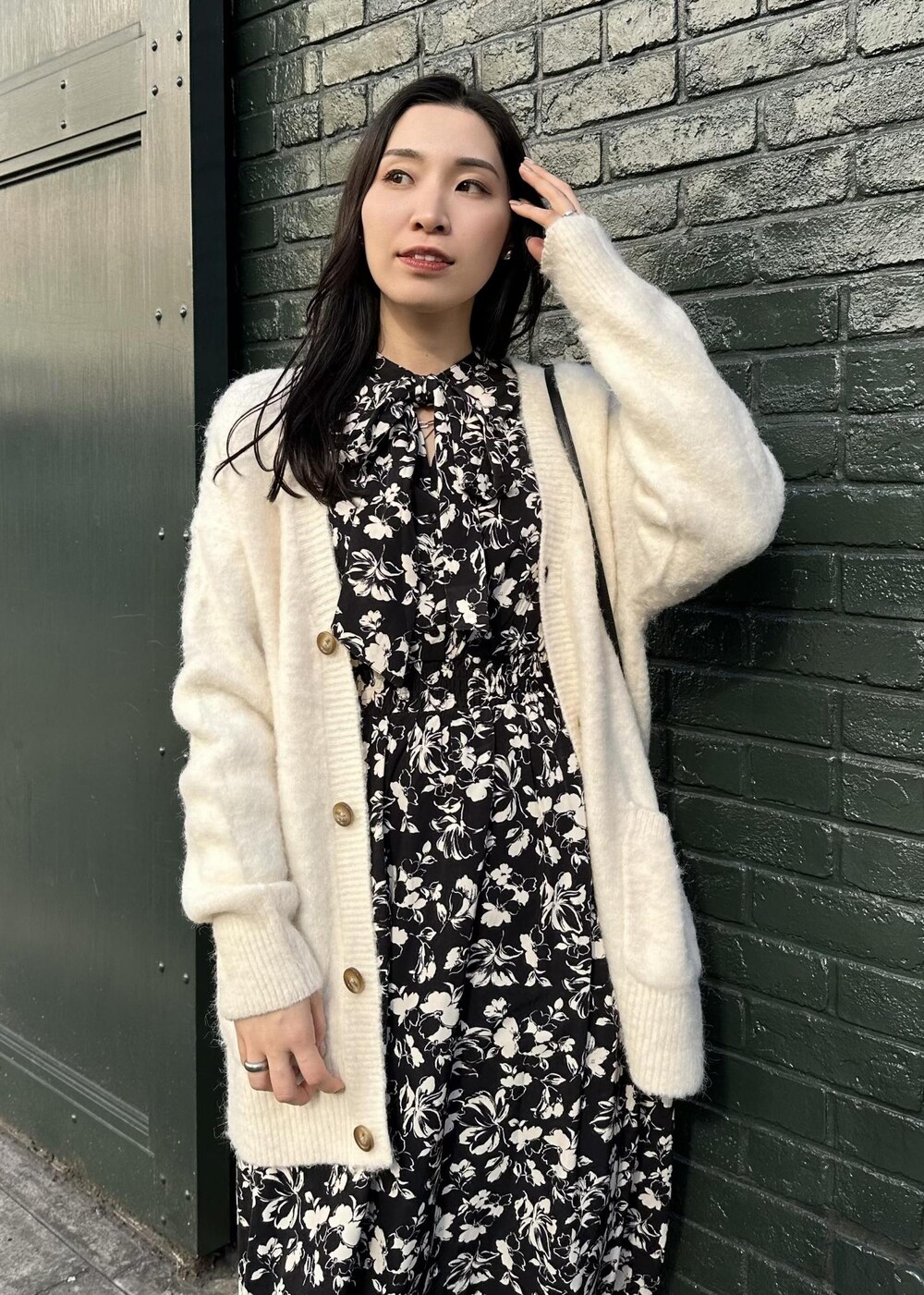 ホワイト系のカーディガン/ボレロ、ブラック系のショルダーバッグ、ブルー系のデニムパンツを着用したレディースの冬コーディネートの2枚目の写真