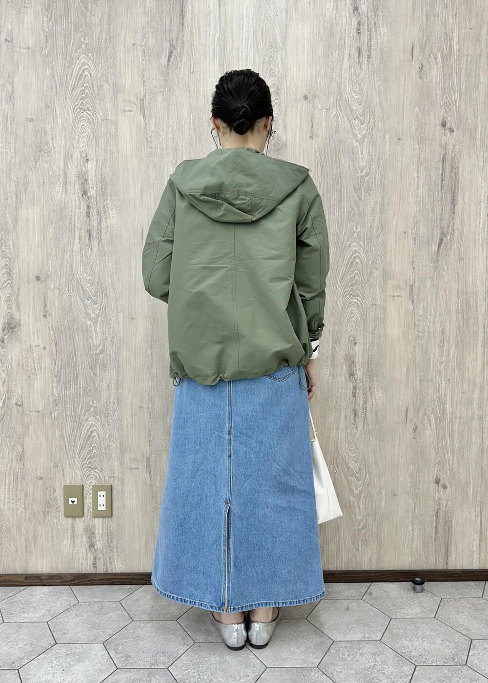 グリーン系のマウンテンパーカー、ホワイト系のTシャツ/カットソー、ブルー系のデニムスカートを着用したレディースの春コーディネートの2枚目の写真