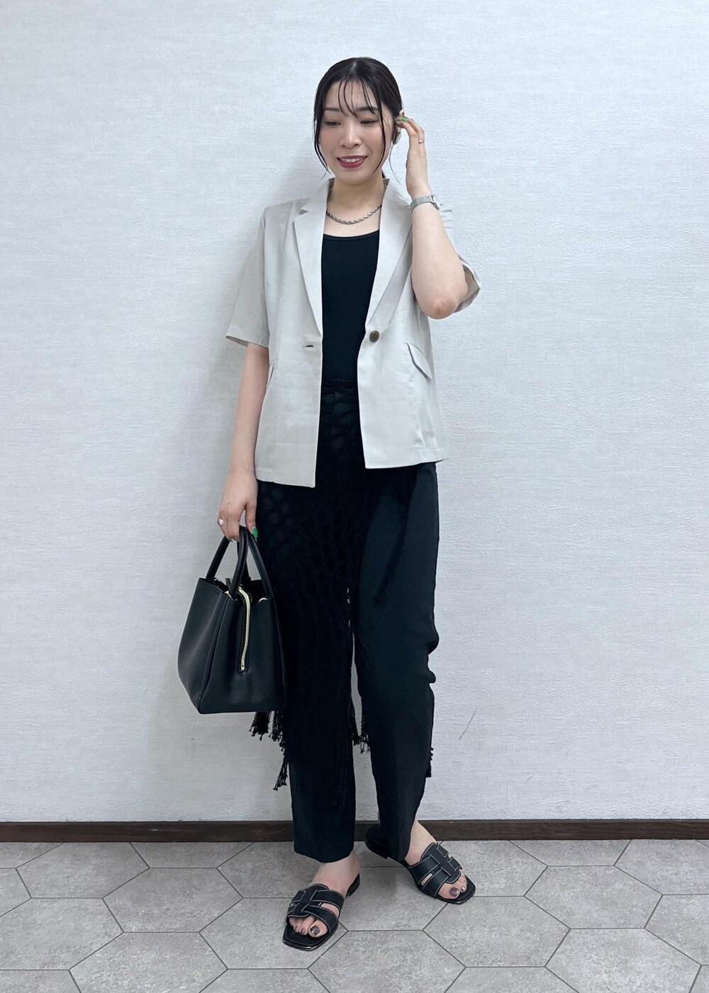 ブラック系のショルダーバッグ、ベージュ系のテーラードジャケット、グレー系のその他パンツを着用したレディースの夏コーディネートの2枚目の写真