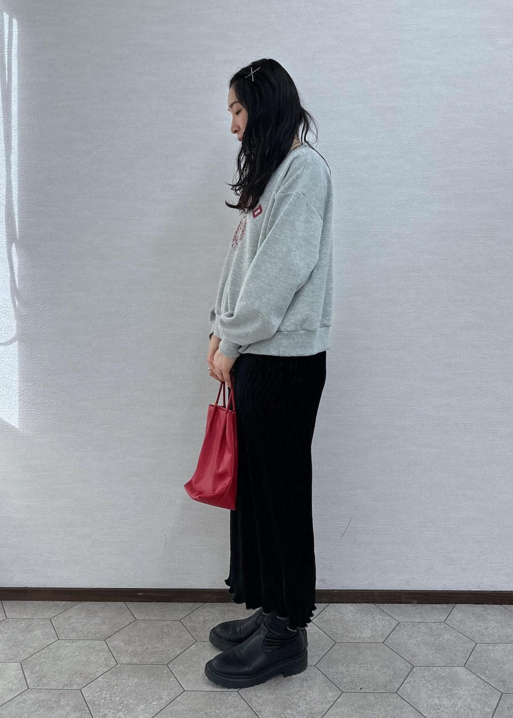 グレー系のスウェット、レッド系のトートバッグ、ブラック系のスカートを着用したレディースの冬コーディネートの4枚目の写真