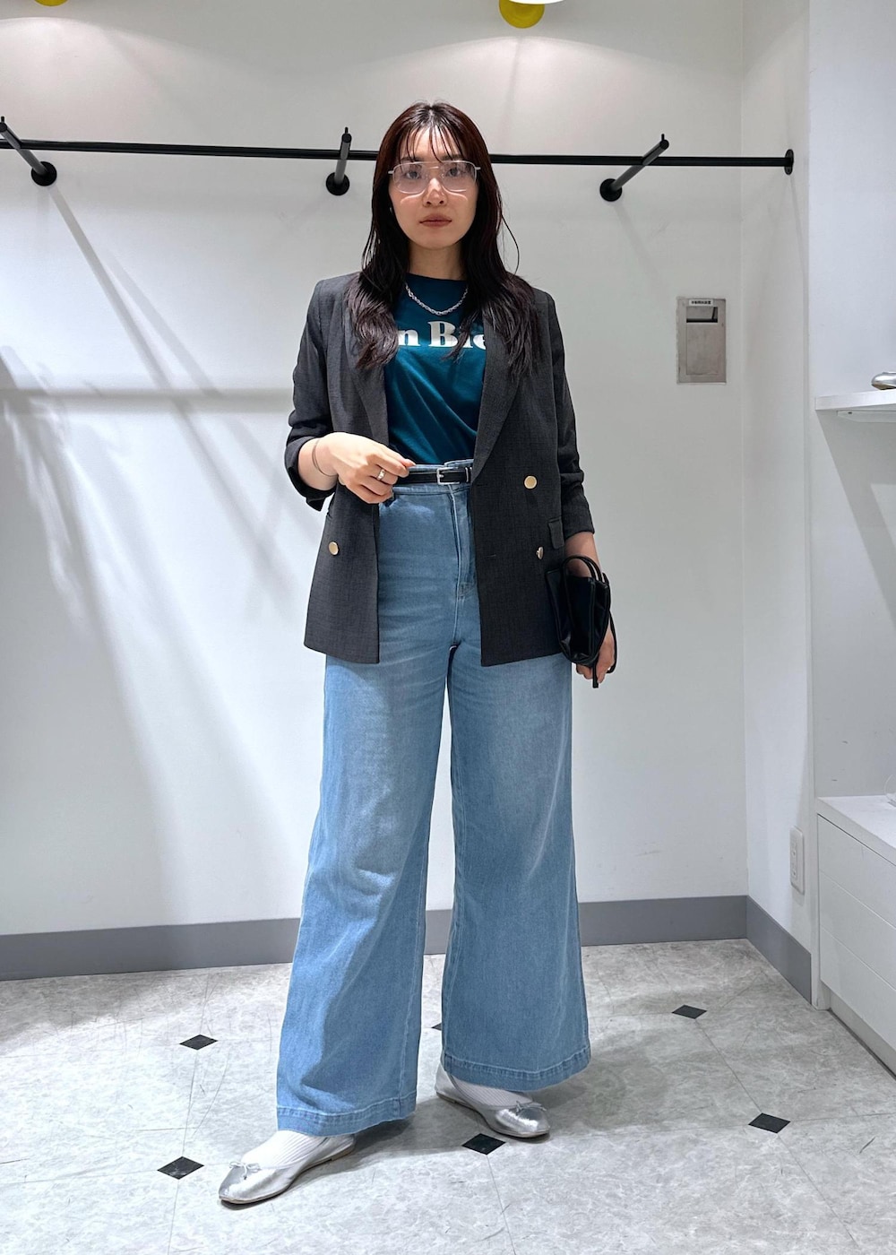 シルバー系のバレエシューズ、ブラック系のトートバッグ、ブルー系のデニムパンツを着用したレディースの夏コーディネートの2枚目の写真