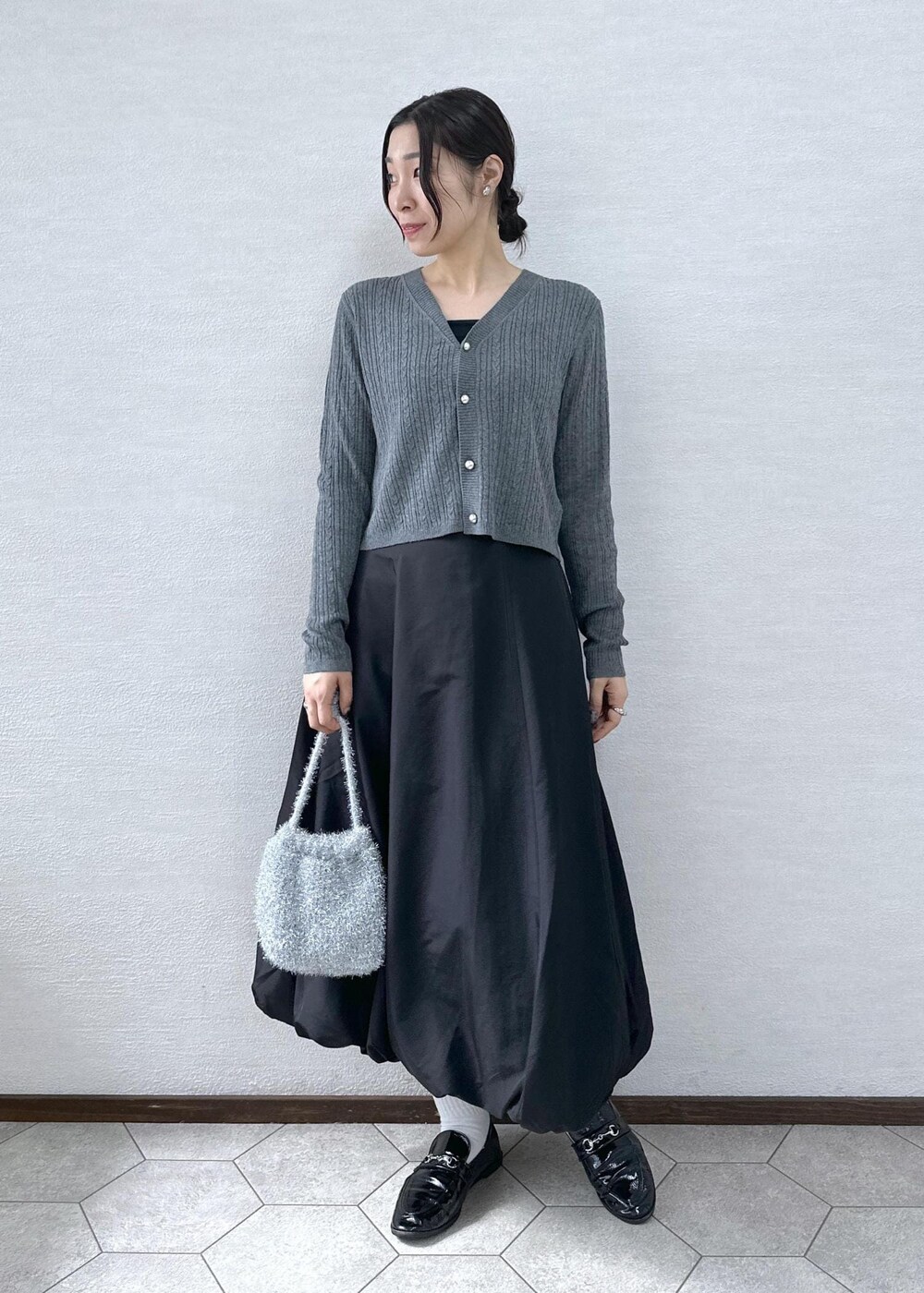 ブラック系のスカート、グレー系のカーディガン/ボレロ、シルバー系のショルダーバッグを着用したレディースの秋コーディネートの4枚目の写真