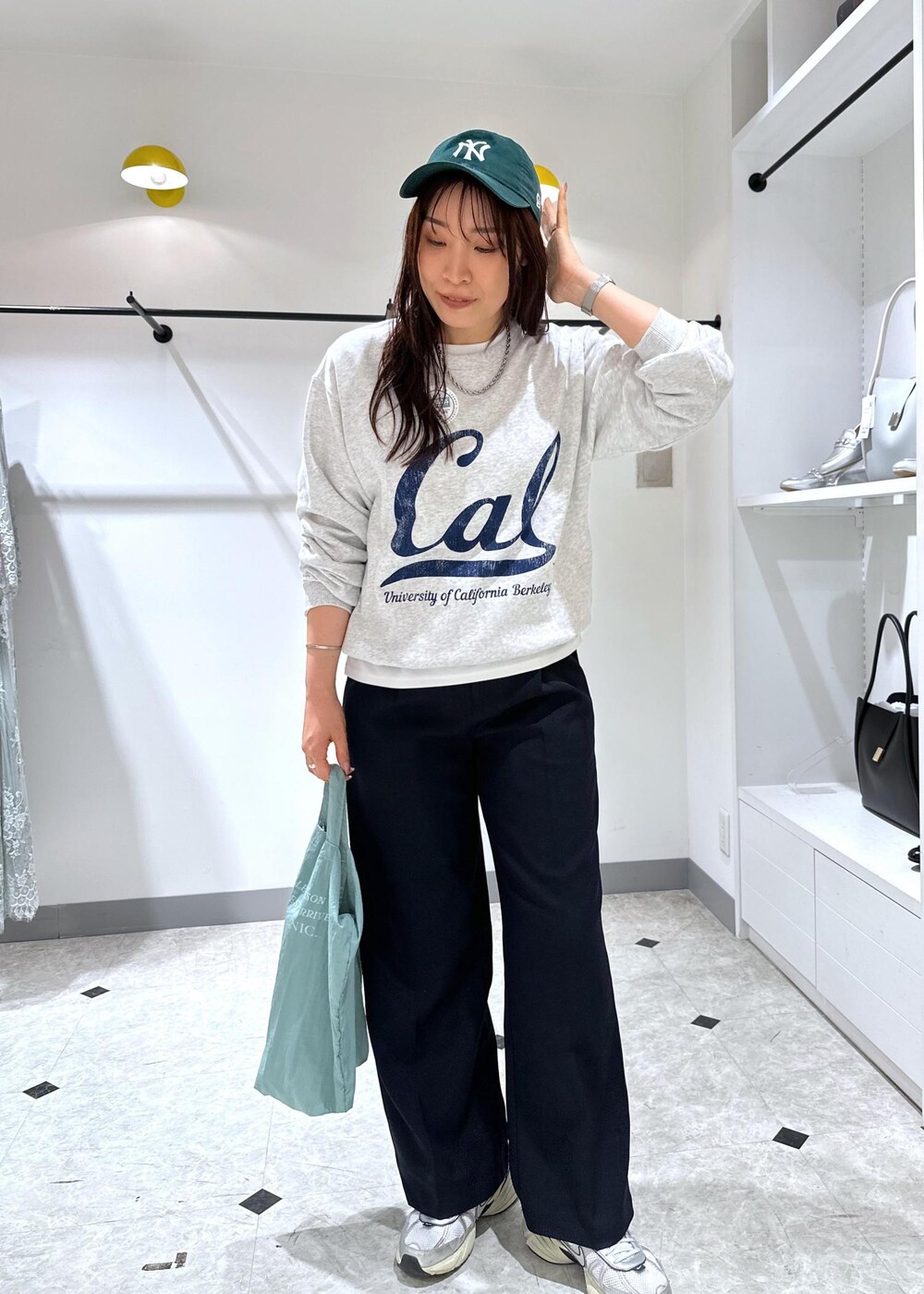 グレー系のスウェット、ブルー系のトートバッグ、ブルー系のスラックスを着用したレディースの夏コーディネートの3枚目の写真