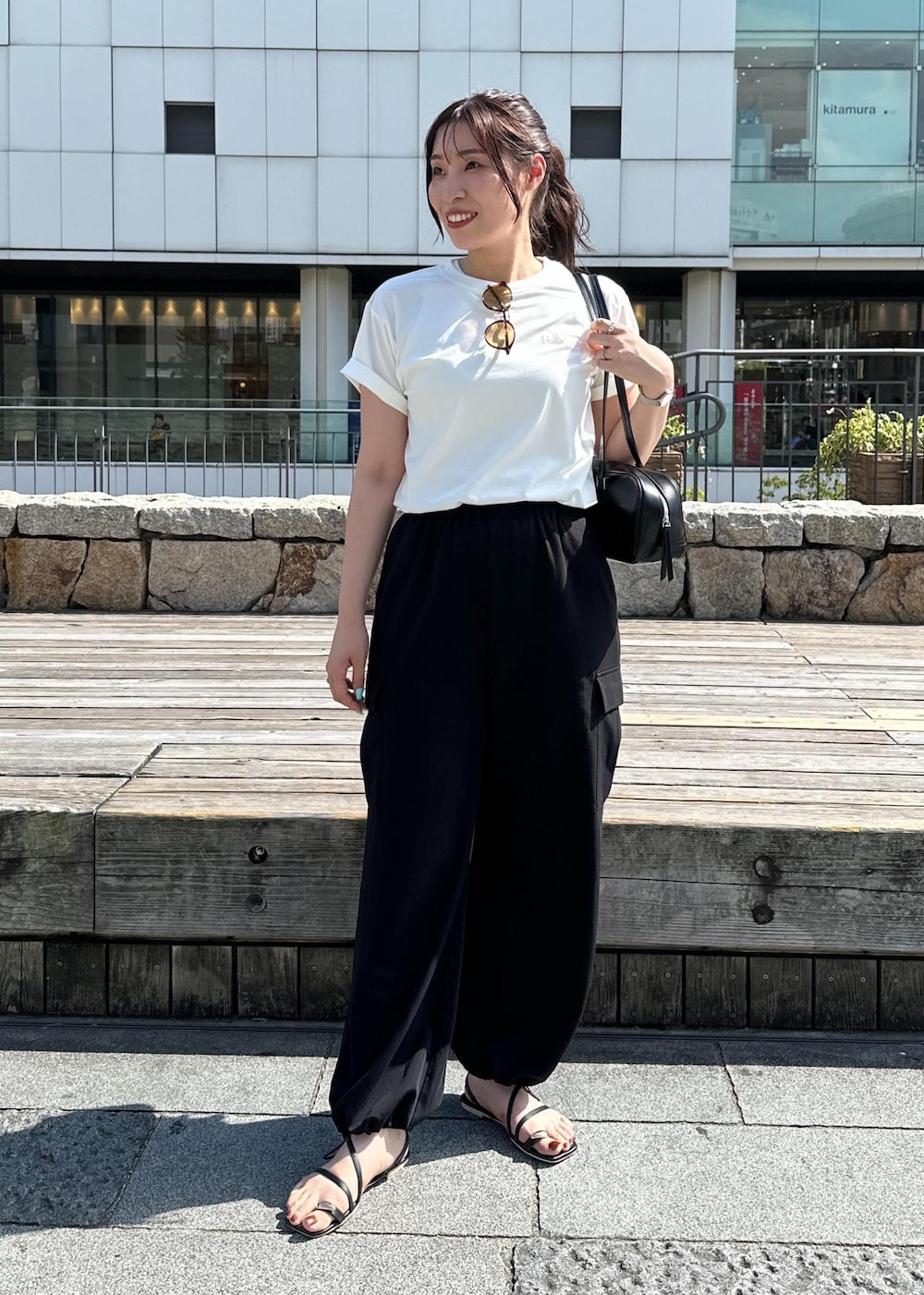 ブラック系のカーゴパンツ、ブラック系のサンダル、ホワイト系のTシャツ/カットソーを着用したレディースの夏コーディネートの2枚目の写真