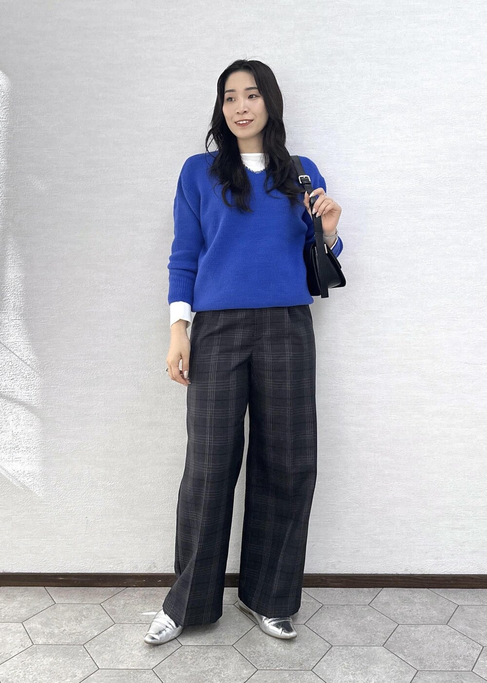 ブラック系のショルダーバッグ、ブルー系のニット/セーター、ホワイト系のTシャツ/カットソーを着用したレディースの秋コーディネートの2枚目の写真