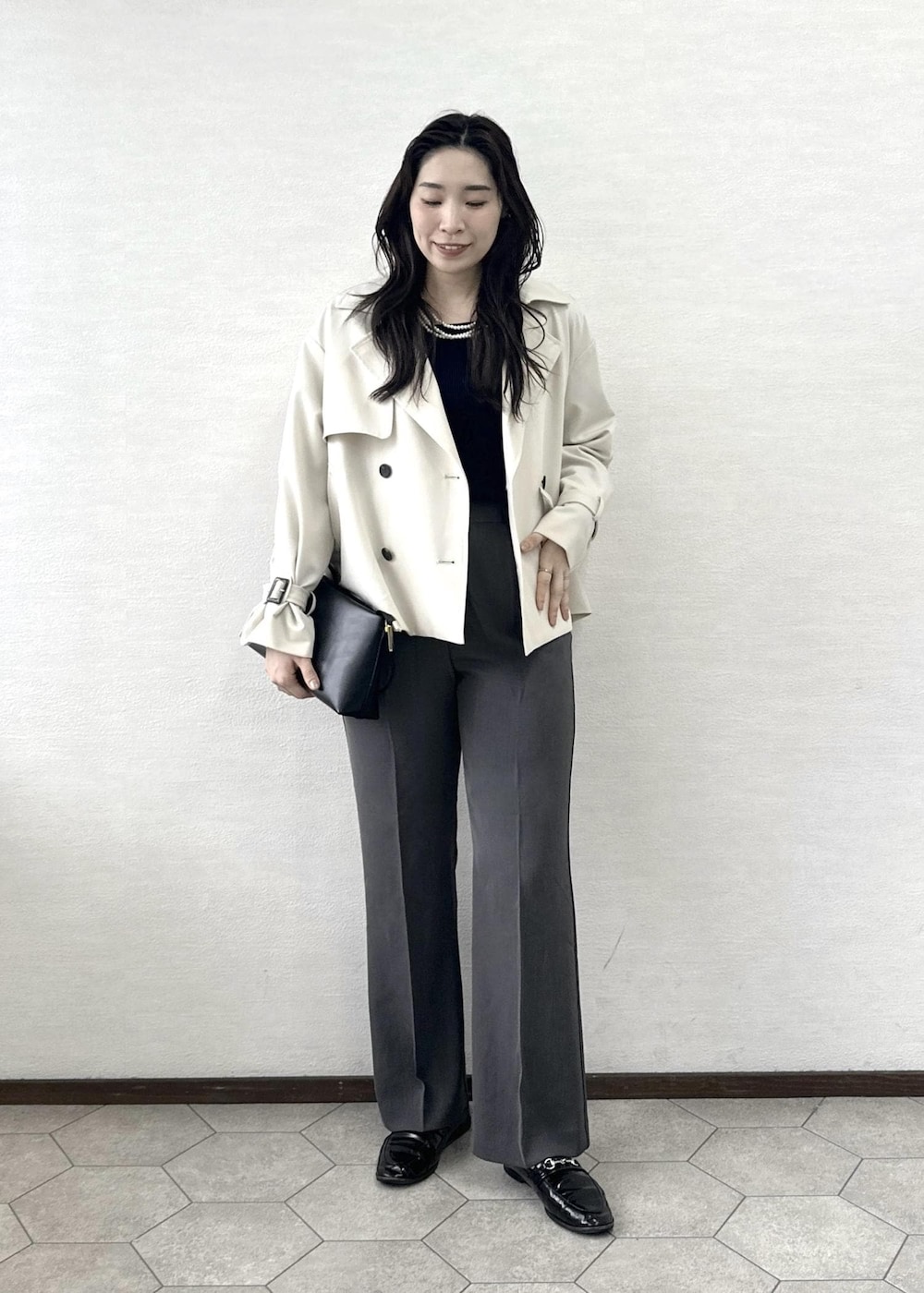 ブラック系のショルダーバッグ、ブルー系のニット/セーター、ベージュ系のトレンチコートを着用したレディースの春コーディネートの2枚目の写真