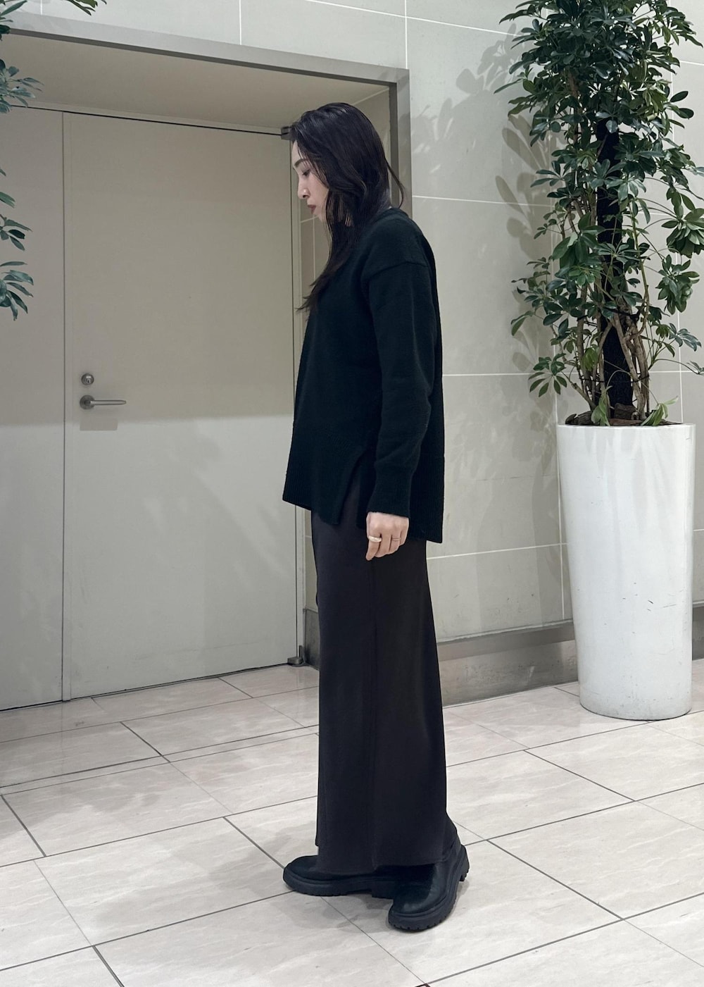 ブラック系のニット/セーター、ブラック系のショルダーバッグ、ブラウン系のスカートを着用したレディースの冬コーディネートの4枚目の写真