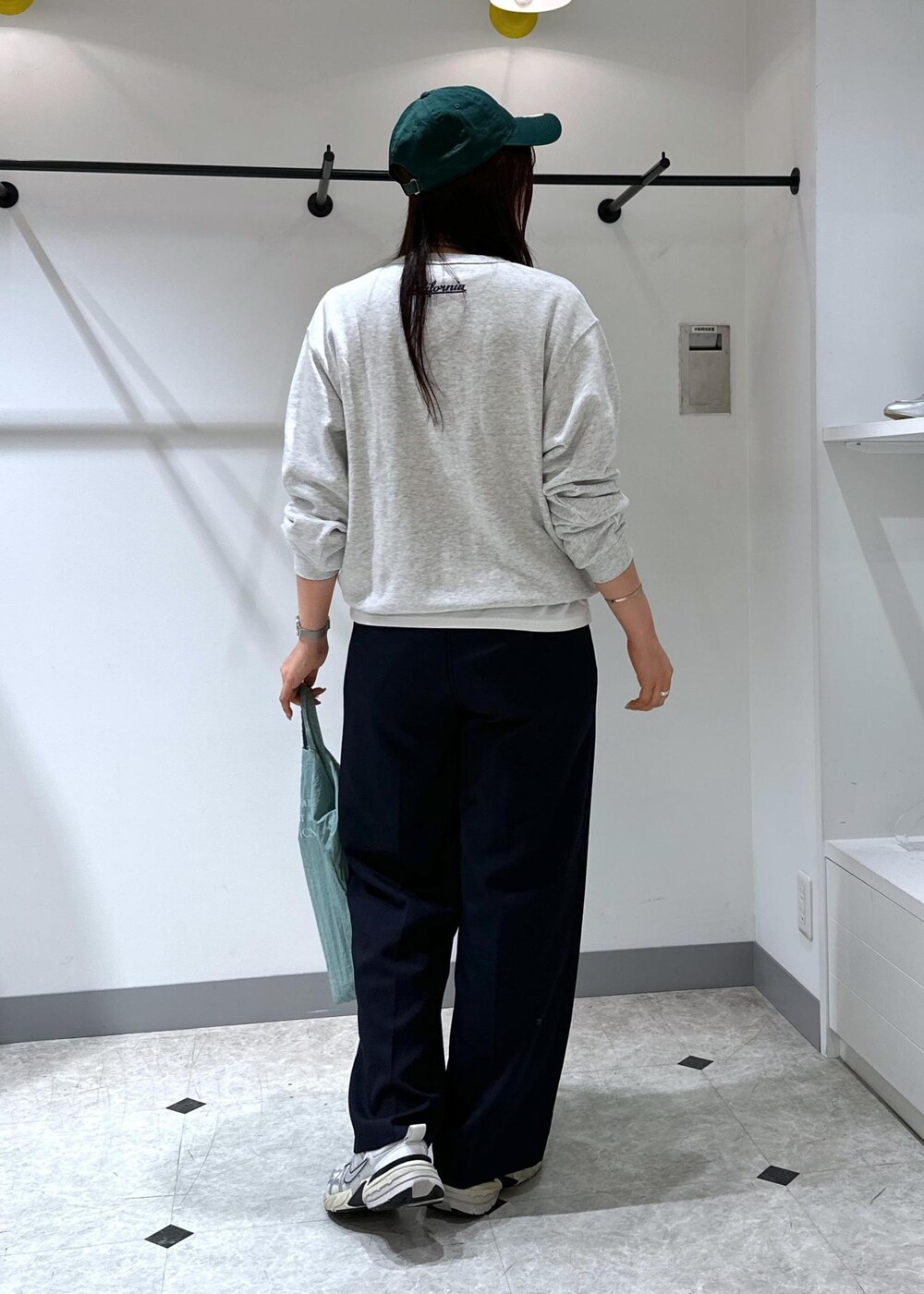 グレー系のスウェット、ブルー系のトートバッグ、ブルー系のスラックスを着用したレディースの夏コーディネートの7枚目の写真