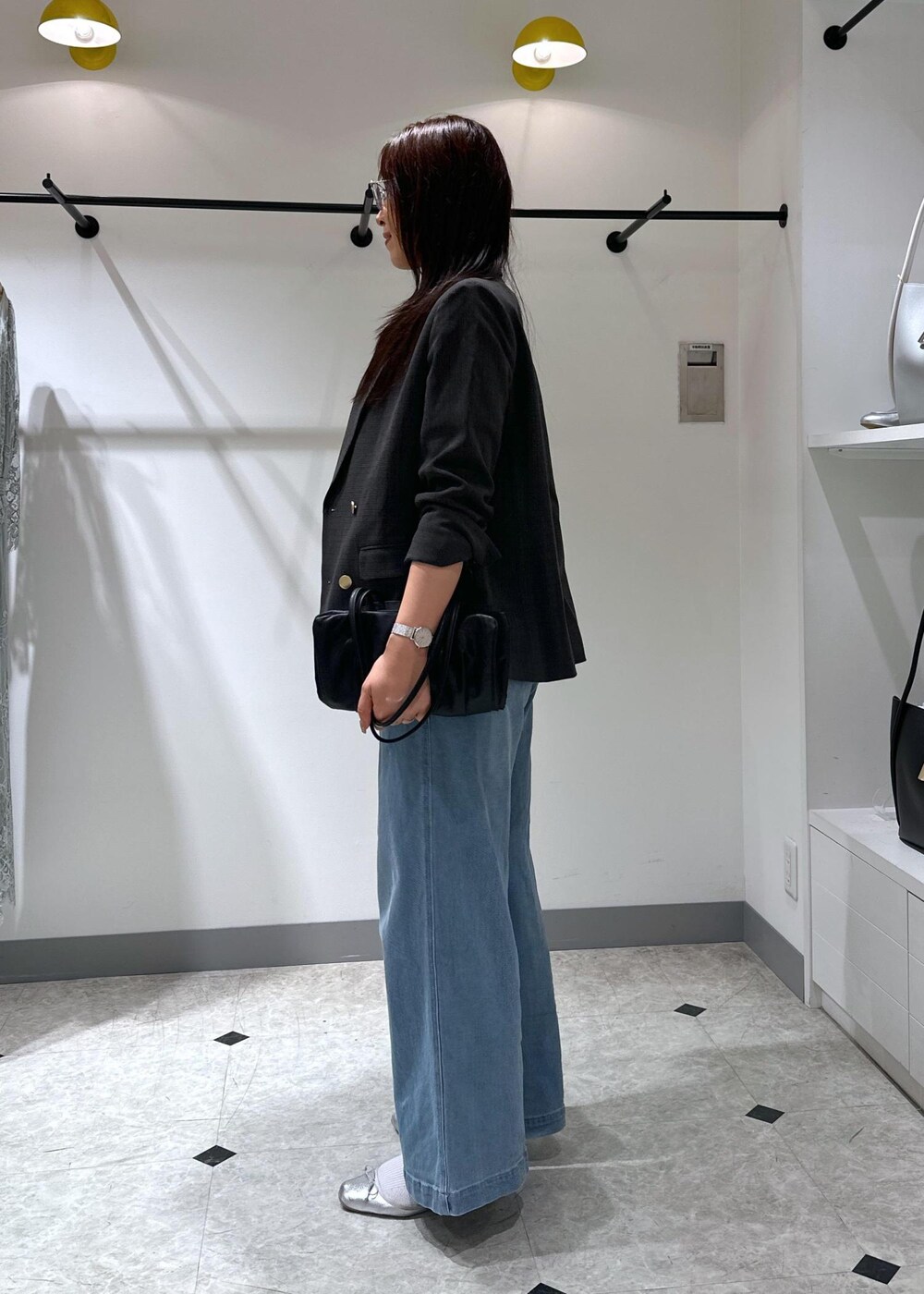 シルバー系のバレエシューズ、ブラック系のトートバッグ、ブルー系のデニムパンツを着用したレディースの夏コーディネートの5枚目の写真