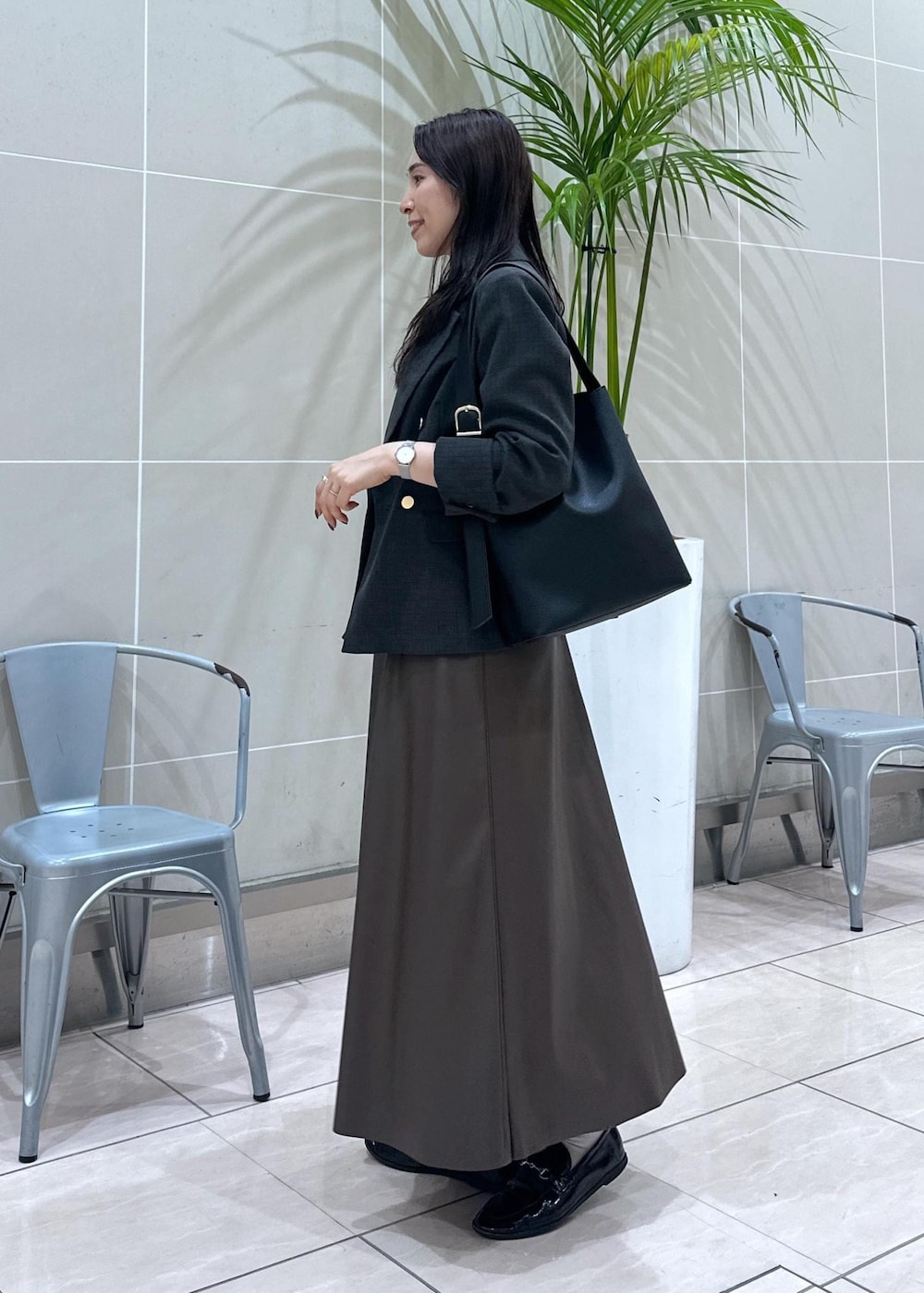 ブラック系のショルダーバッグ、ブラック系のテーラードジャケット、ブラウン系のスカートを着用したレディースの秋コーディネートの5枚目の写真