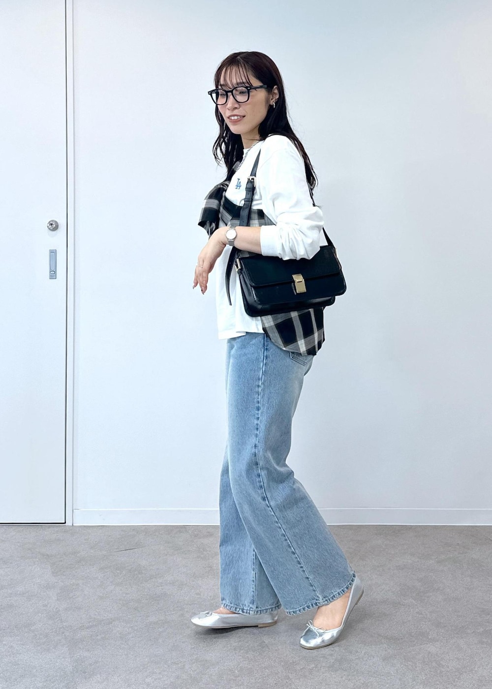 ブルー系のデニムパンツ、シルバー系のバレエシューズ、ブラック系のショルダーバッグを着用したレディースの夏コーディネートの2枚目の写真