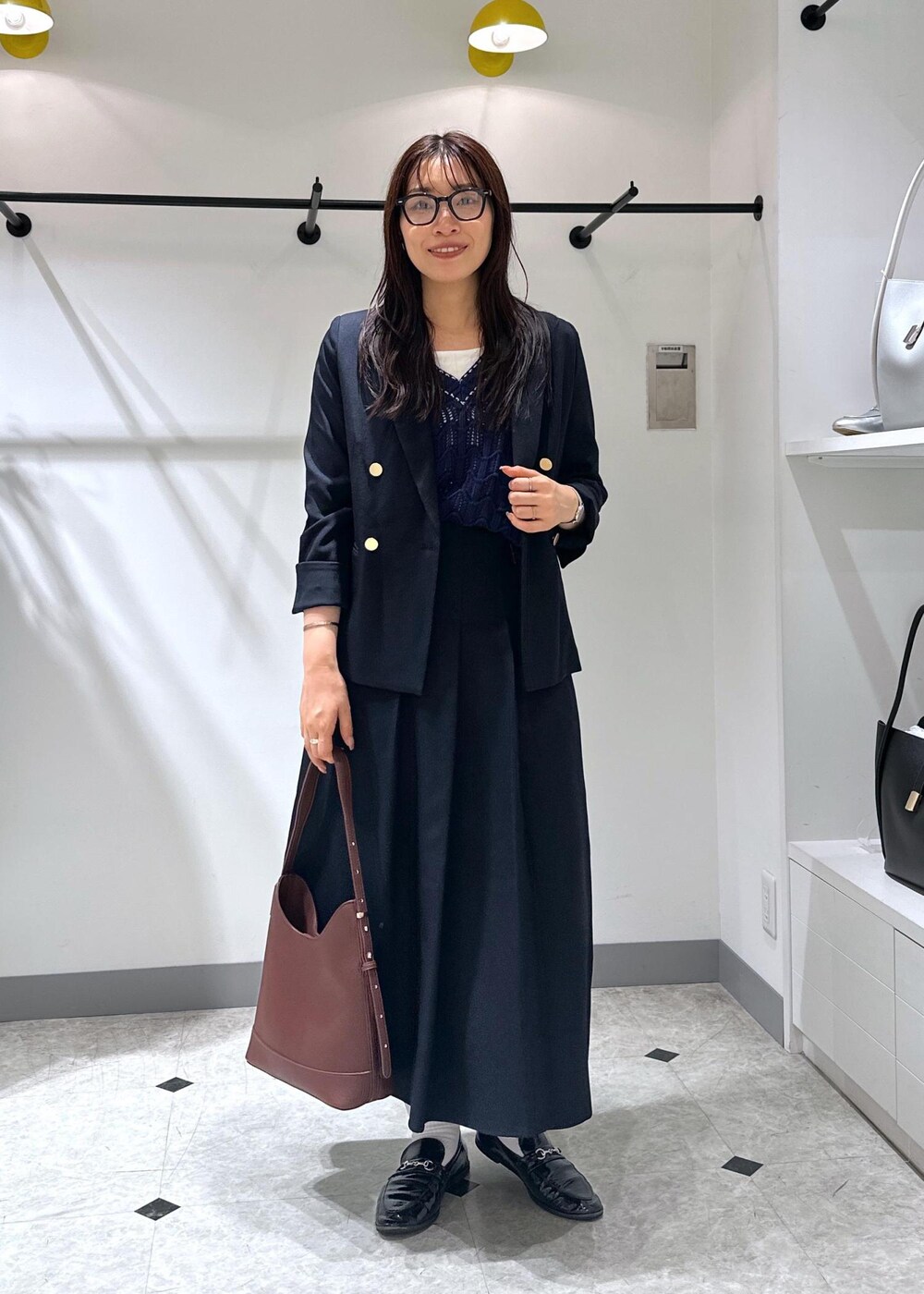 ブルー系のベスト、レッド系のショルダーバッグ、ホワイト系のタンクトップを着用したレディースの夏コーディネートの2枚目の写真