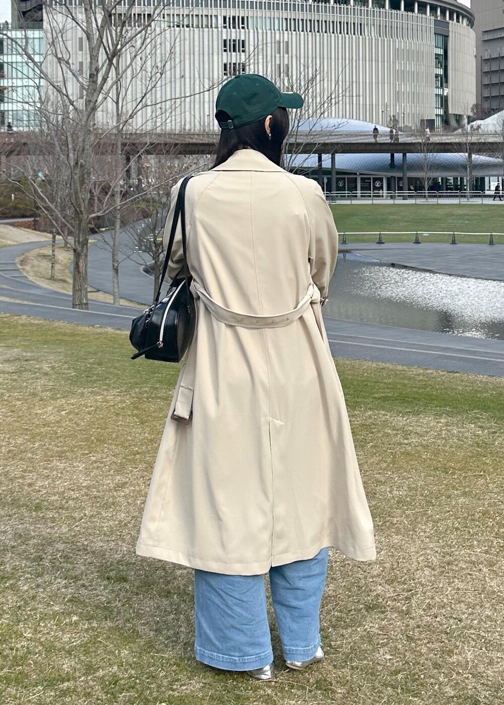 ブラック系のボストンバッグ、ブルー系のベスト、ベージュ系のトレンチコートを着用したレディースの冬コーディネートの4枚目の写真