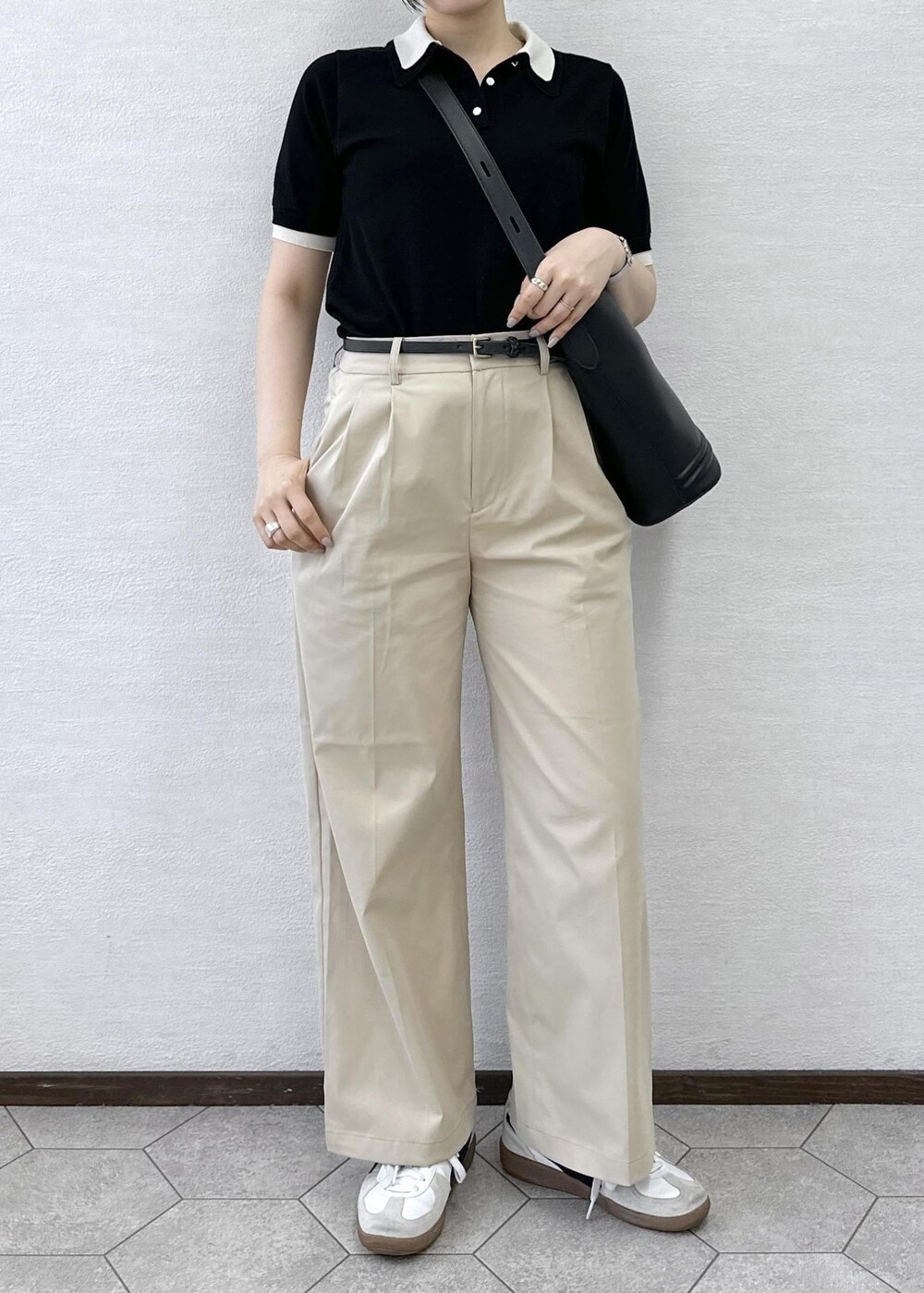 ベージュ系のチノパンツ、ブラック系のトートバッグ、ブラック系のポロシャツを着用したレディースの春コーディネートの6枚目の写真