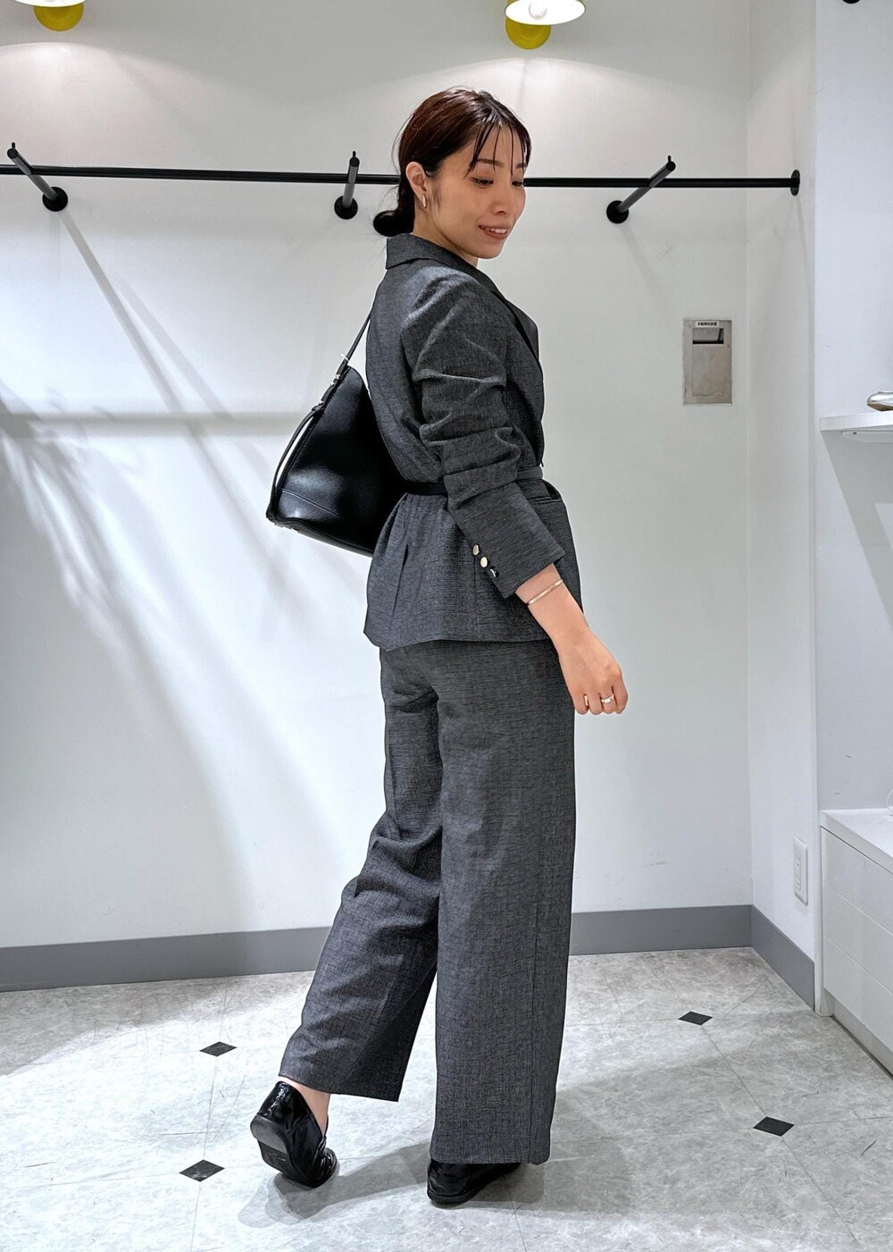 ブラック系のタンクトップ、グレー系のテーラードジャケット、グレー系のスラックスを着用したレディースの夏コーディネートの6枚目の写真