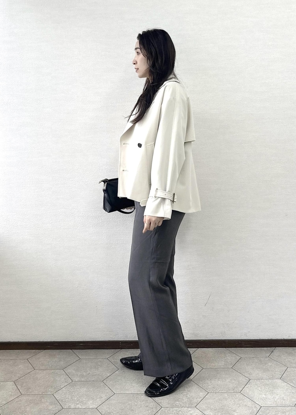 ブラック系のショルダーバッグ、ブルー系のニット/セーター、ベージュ系のトレンチコートを着用したレディースの春コーディネートの3枚目の写真