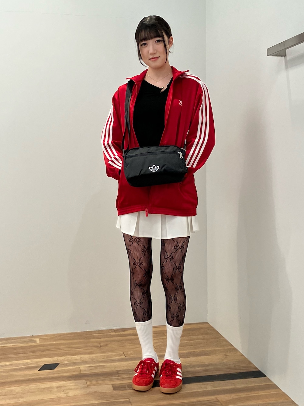 レッド系のジャージ、ブラック系のショルダーバッグ、レッド系のスニーカーを着用したレディースの冬コーディネートの2枚目の写真