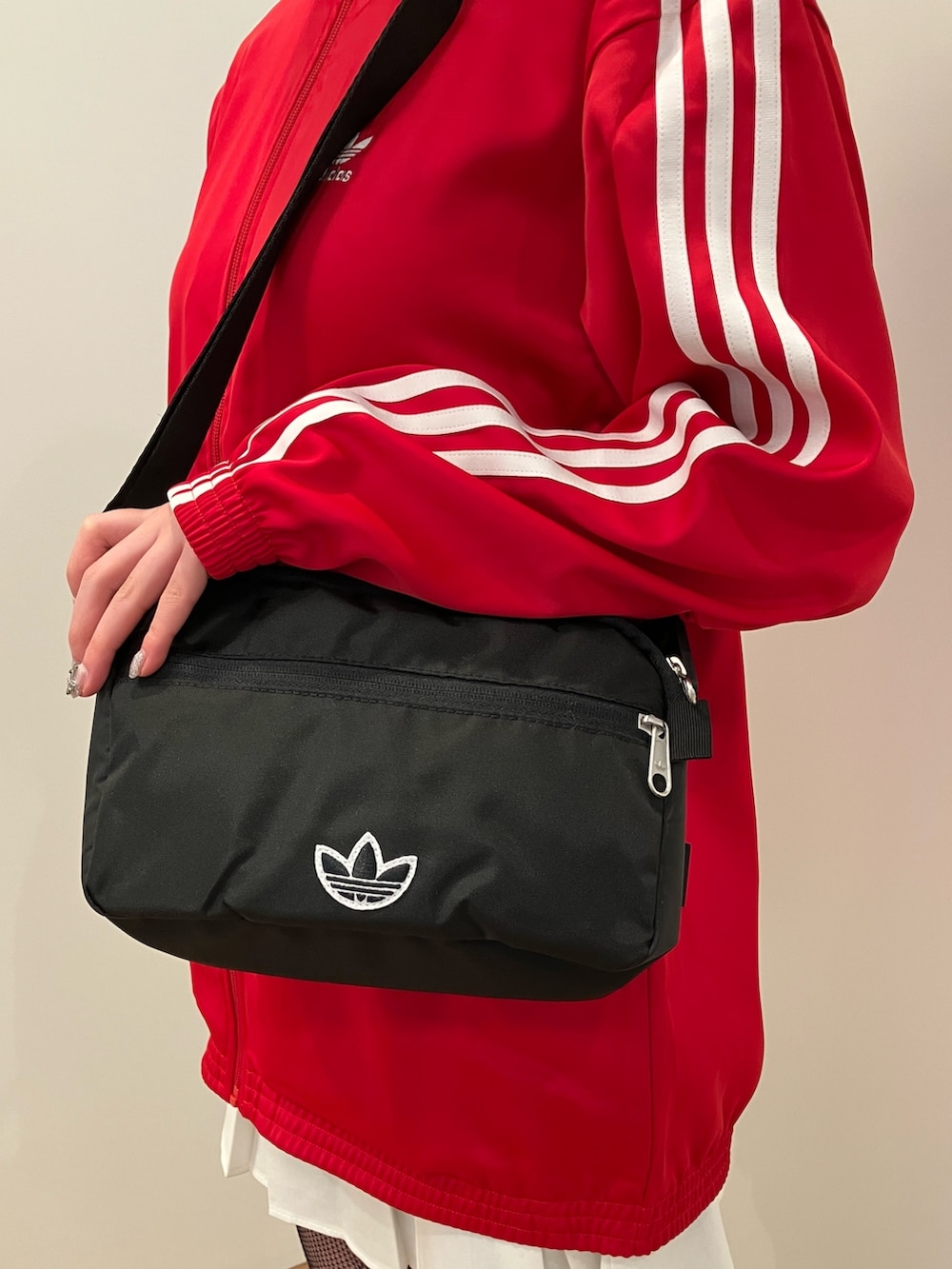 レッド系のジャージ、ブラック系のショルダーバッグ、レッド系のスニーカーを着用したレディースの冬コーディネートの3枚目の写真