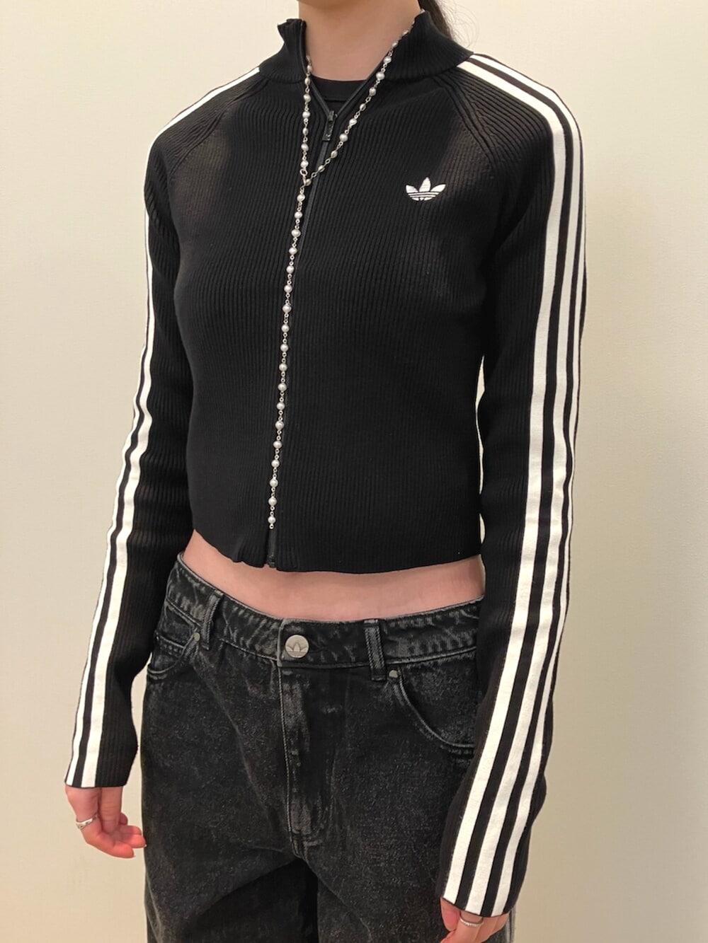 ピンク系のスニーカー、ブラック系のニット/セーター、ブラック系のデニムパンツを着用したレディースの秋コーディネートの2枚目の写真