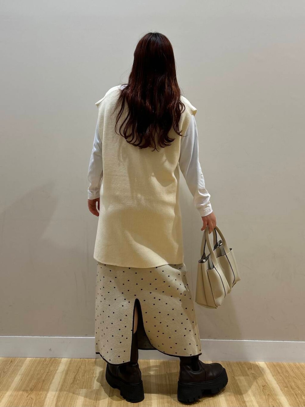 ブラウン系のハンドバッグ、ブラウン系のノーカラーコート、ホワイト系のスカートを着用したレディースの冬コーディネートの8枚目の写真