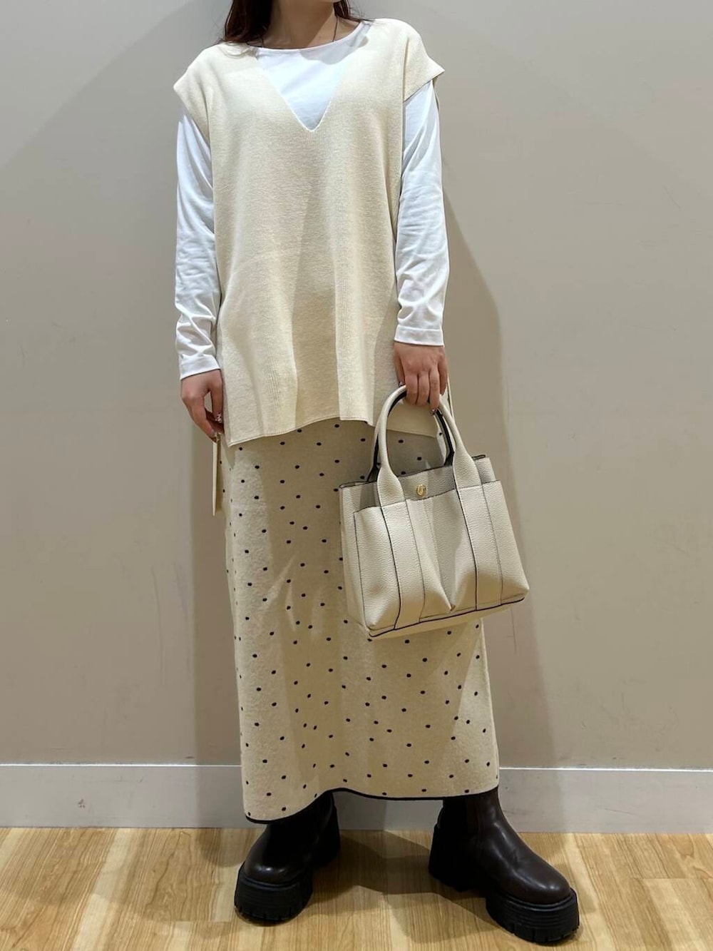 ブラウン系のハンドバッグ、ブラウン系のノーカラーコート、ホワイト系のスカートを着用したレディースの冬コーディネートの10枚目の写真