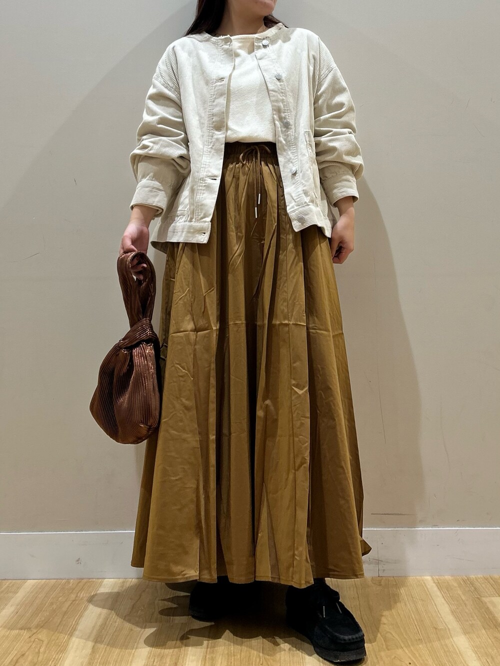 ホワイト系のノーカラージャケット、ホワイト系のTシャツ/カットソー、イエロー系のスカートを着用したレディースの秋コーディネートの5枚目の写真