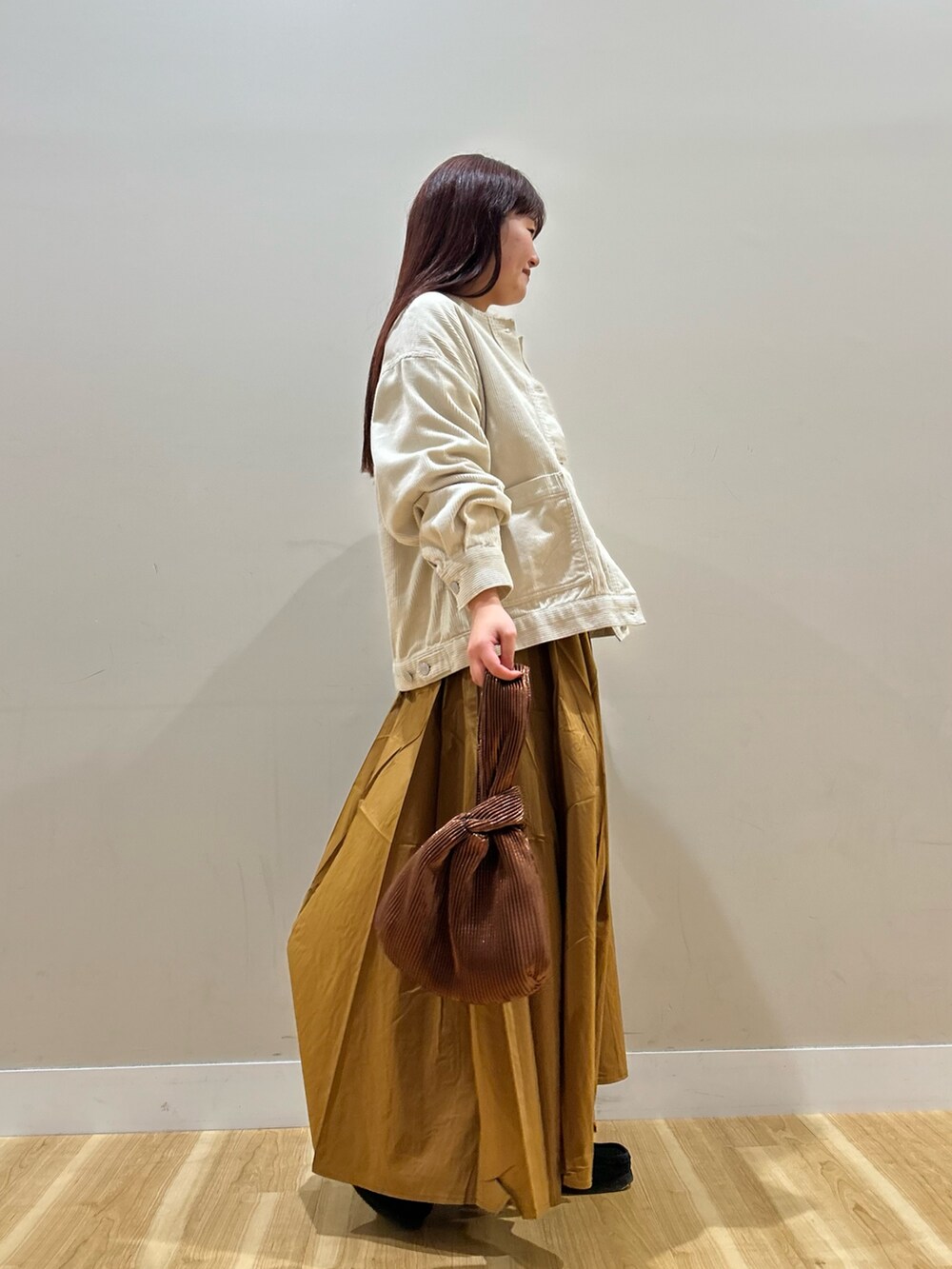 ホワイト系のノーカラージャケット、ホワイト系のTシャツ/カットソー、イエロー系のスカートを着用したレディースの秋コーディネートの2枚目の写真