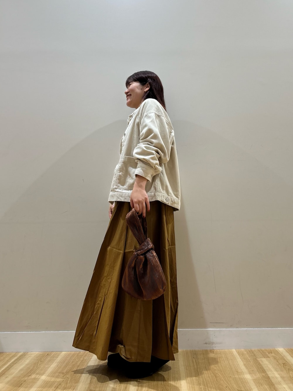 ホワイト系のノーカラージャケット、ホワイト系のTシャツ/カットソー、イエロー系のスカートを着用したレディースの秋コーディネートの4枚目の写真