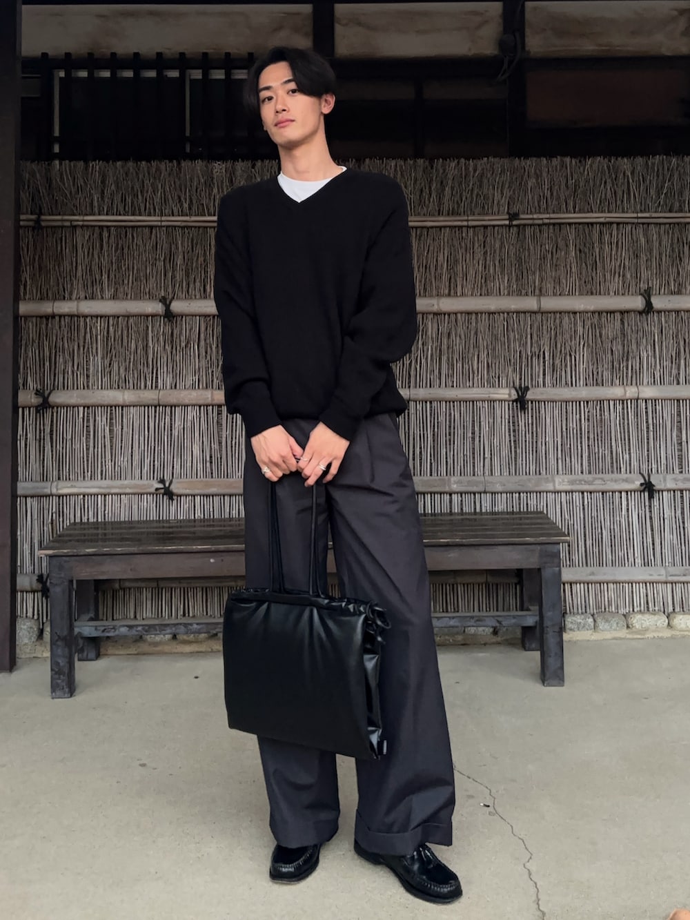 ブラック系のニット/セーター、グレー系のスラックス、ブラック系のショルダーバッグを着用したメンズの春コーディネートの2枚目の写真