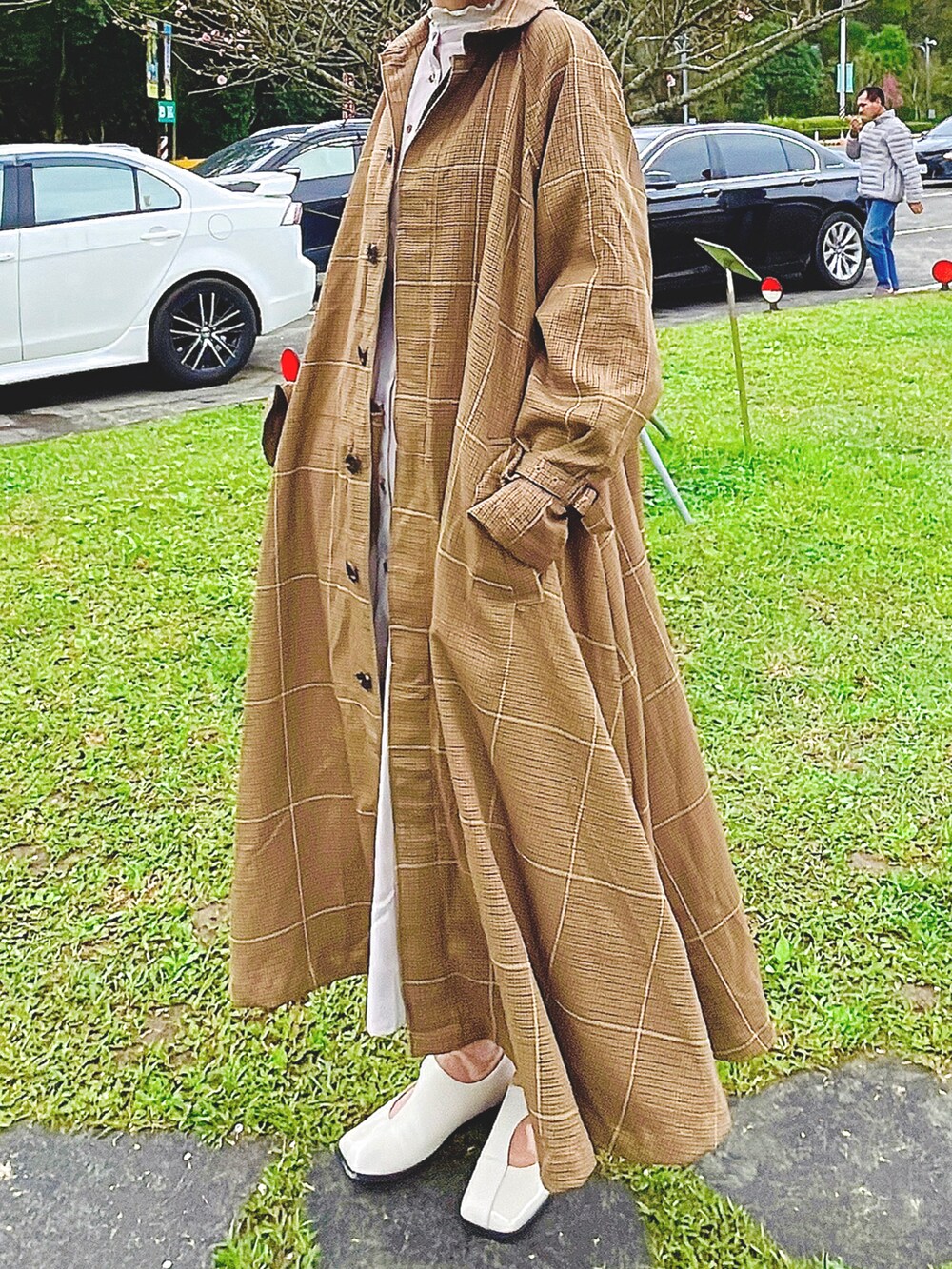 ベージュ系のトレンチコート、グレー系のワンピースを着用したレディースの冬コーディネートの2枚目の写真